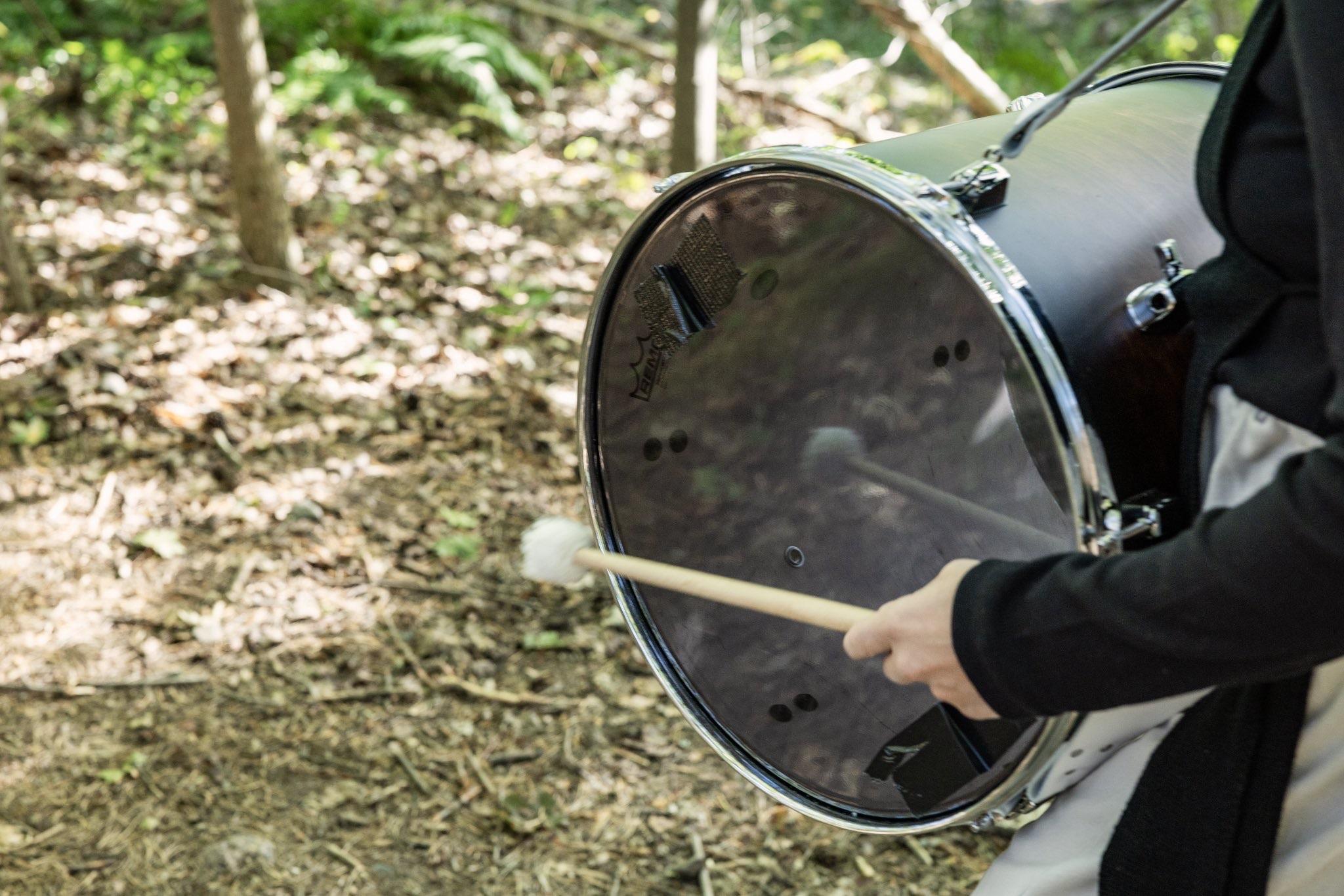 Dancers with marching drums performing in a forest.