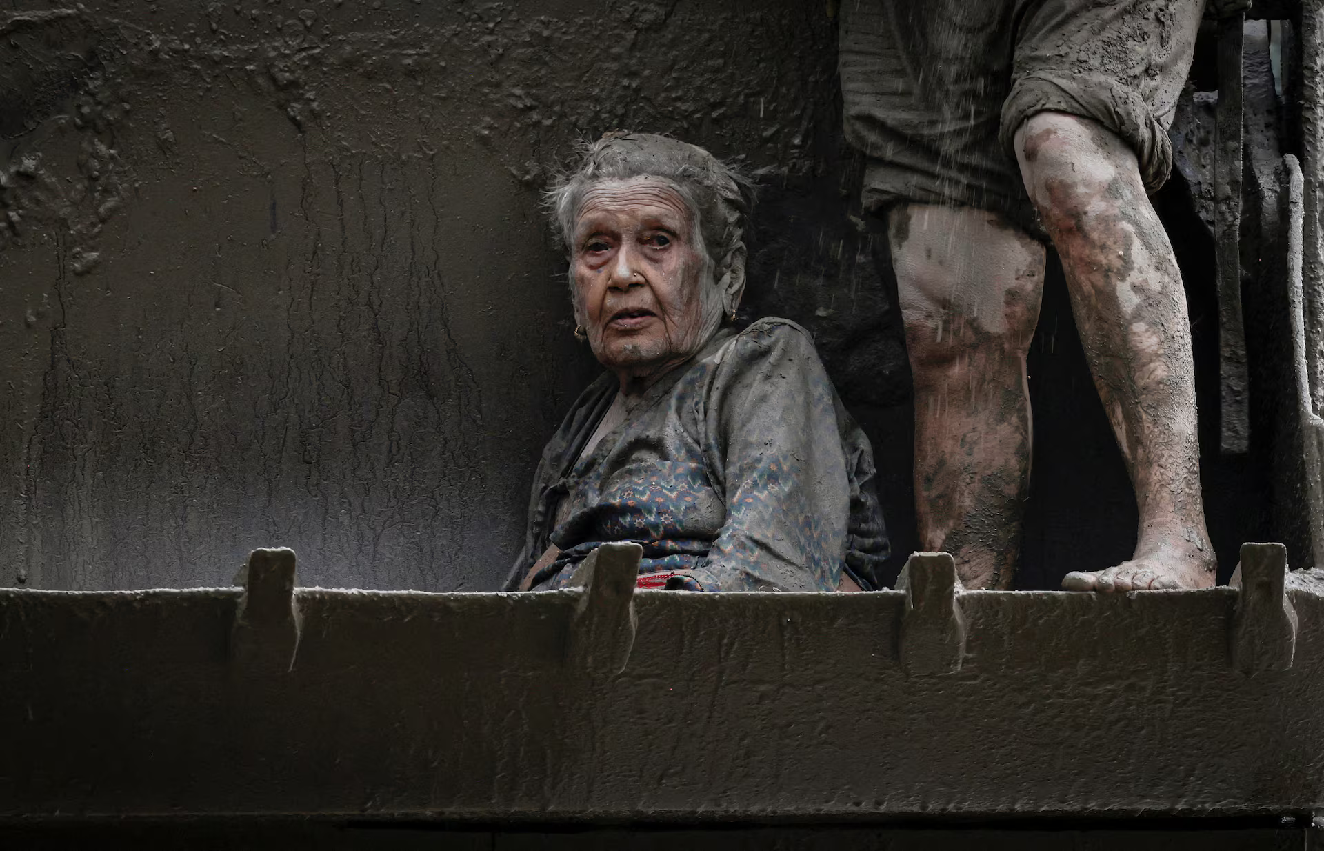 An elderly woman survivor covered by mud.