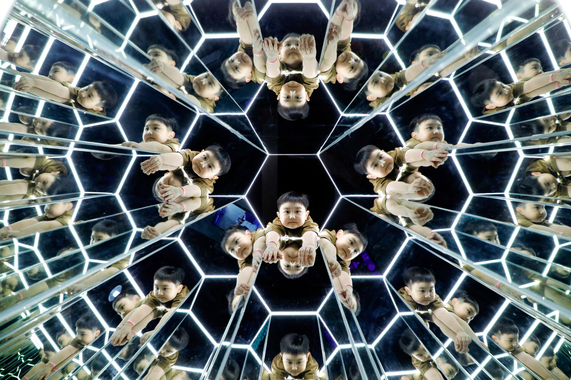 A child's image reflected multiple times in a hexagonal structure.