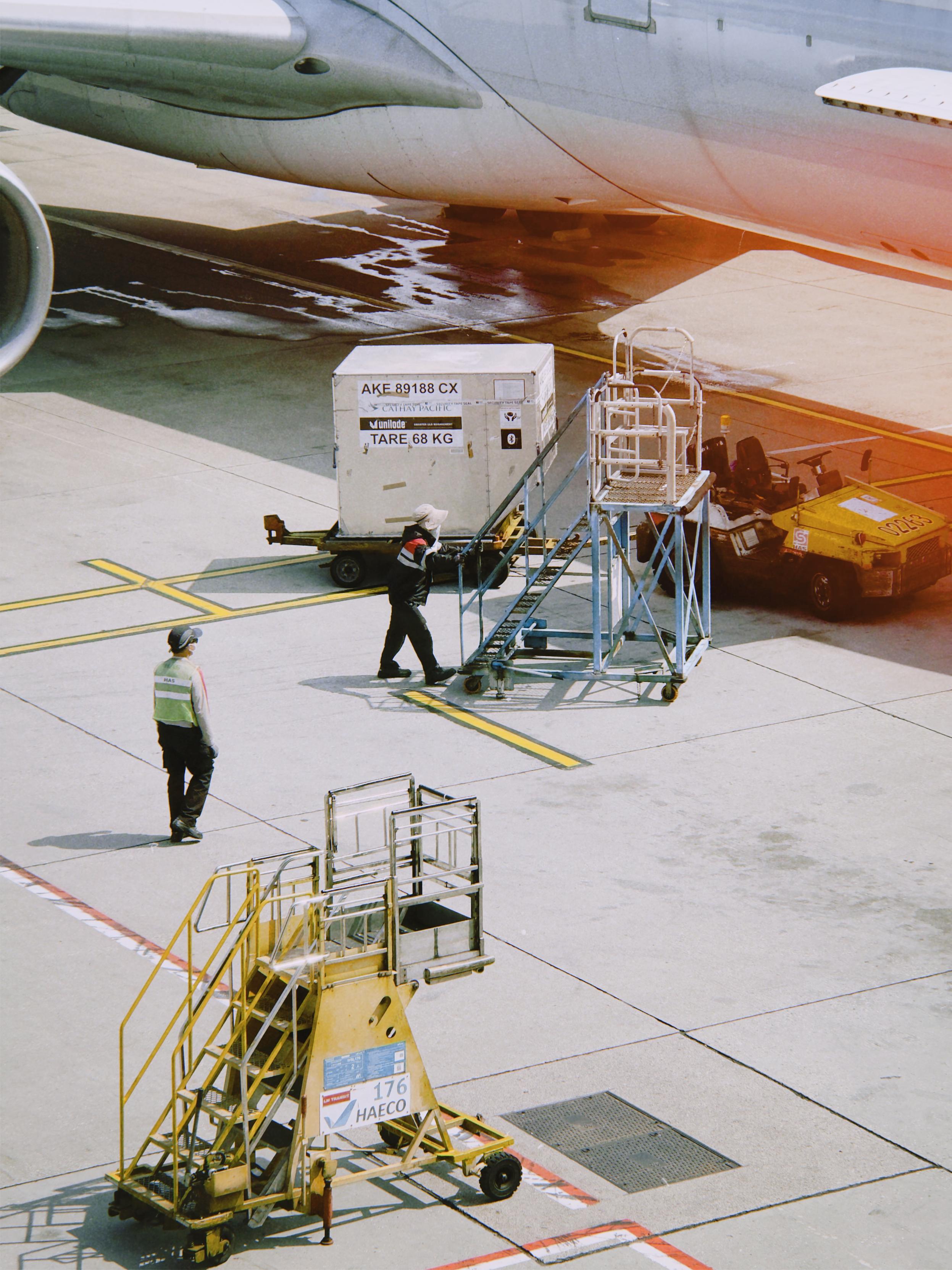 Ground crew loading cargo onto an airplane at an airport tarmac.