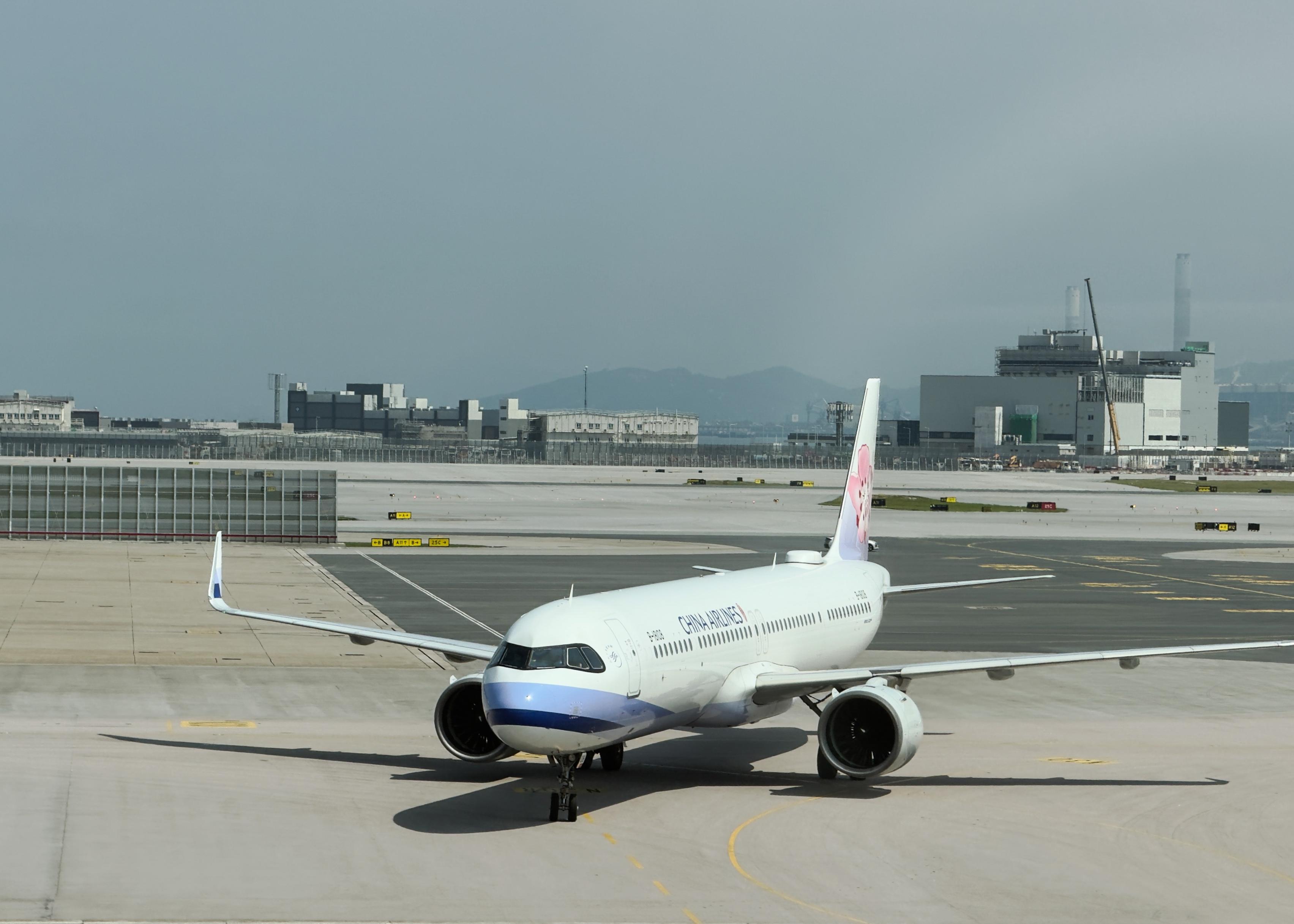 一架中国南方航空的白色飞机停在跑道上，背景是机场建筑和远山。