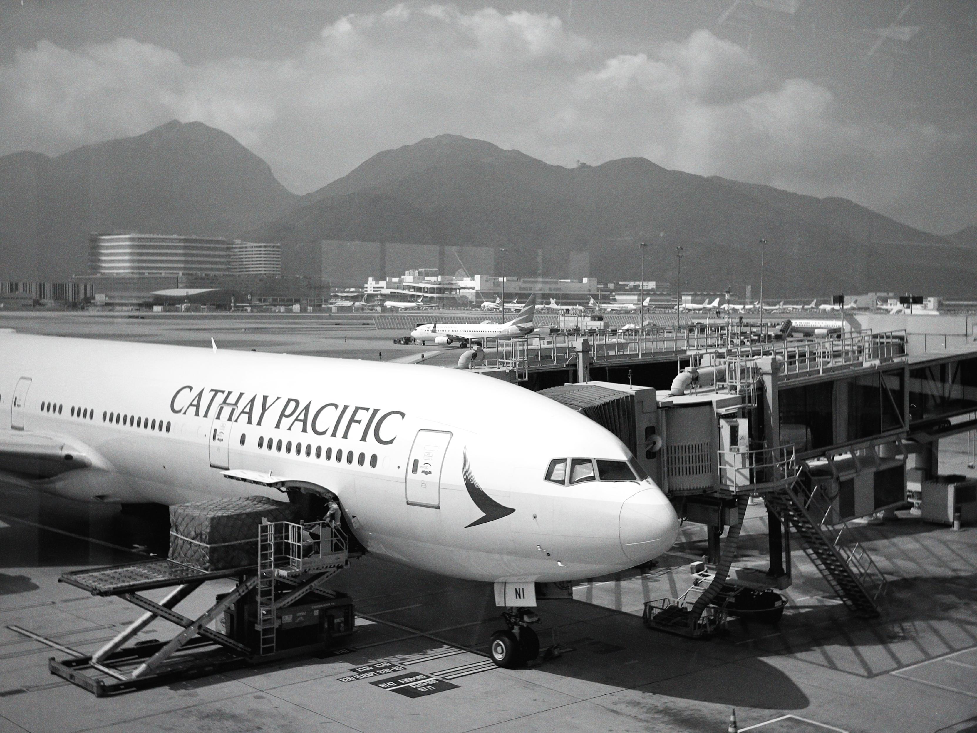 香港快运航空飞机在机场停靠，背景是山脉和云朵。
