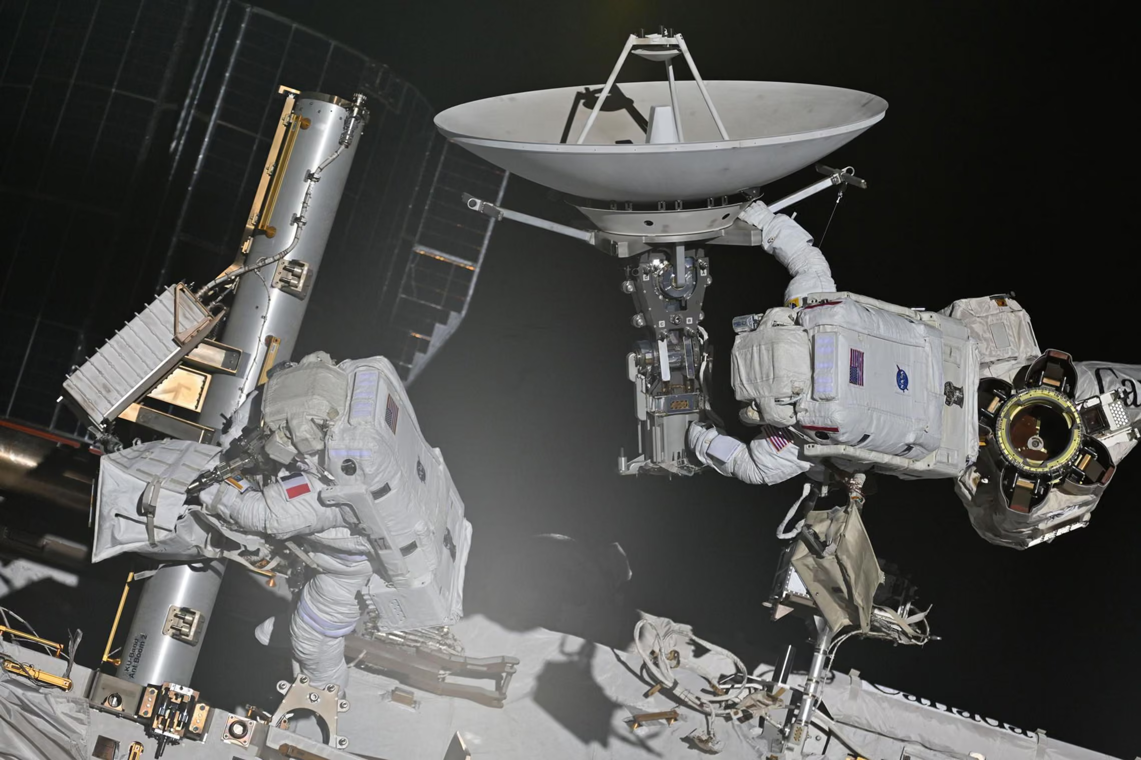 A spacewalk of two astronauts outside the International Space Station.