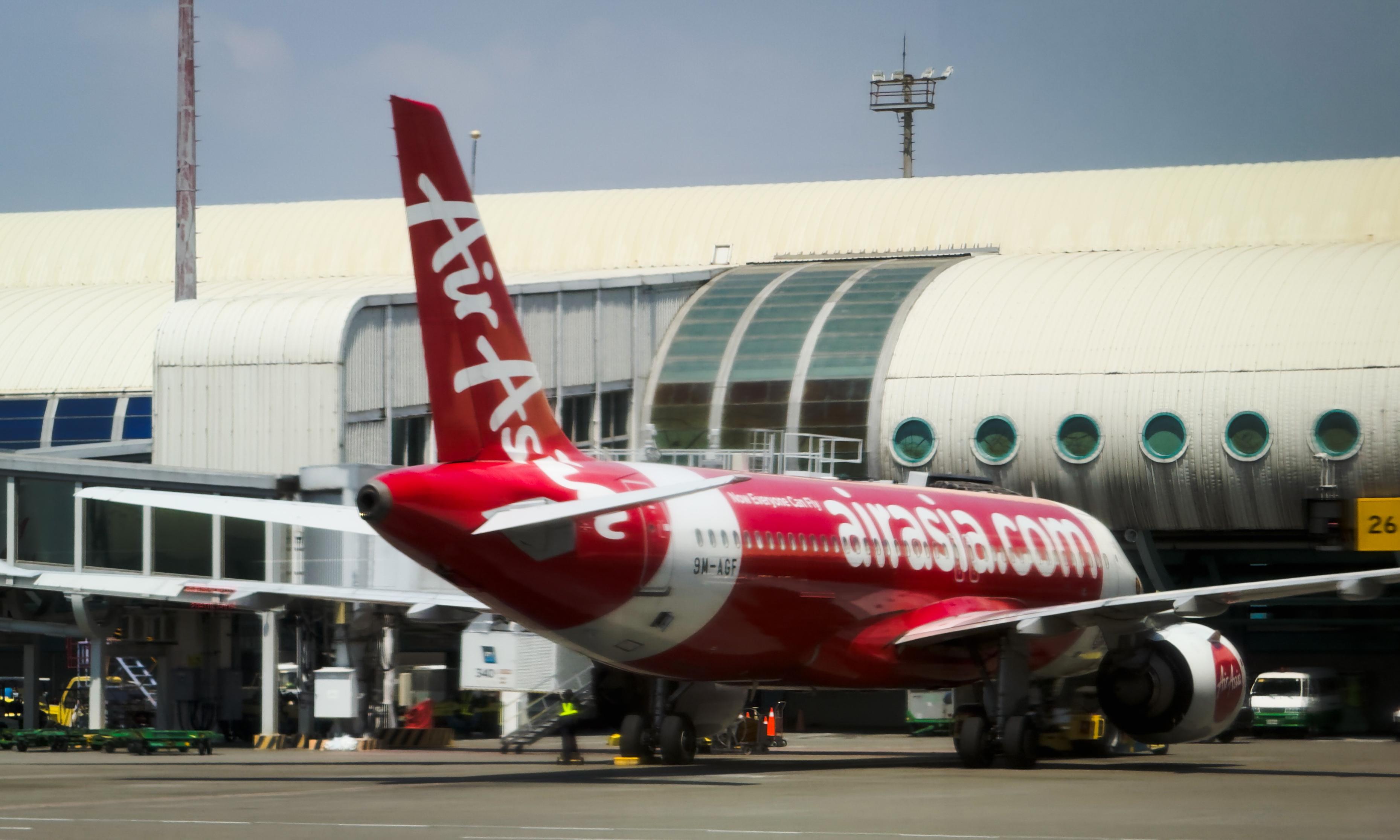 一架红色的“airasia.com”飞机停在机场登机口。