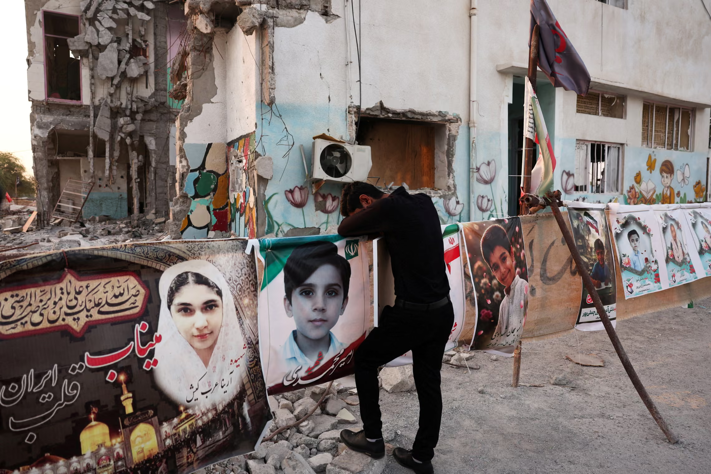 A man mourns in front of pictures of children who were killed.