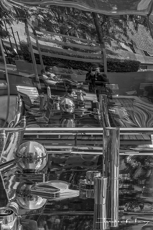 Self-portrait, using reflective metallic surface, creating distorted lines and shapes, along with straight lines.