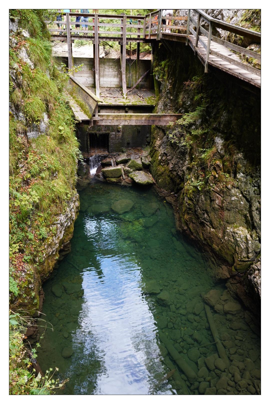 Klamm mit grünem Wasser und Holzbrücke über das Wasser