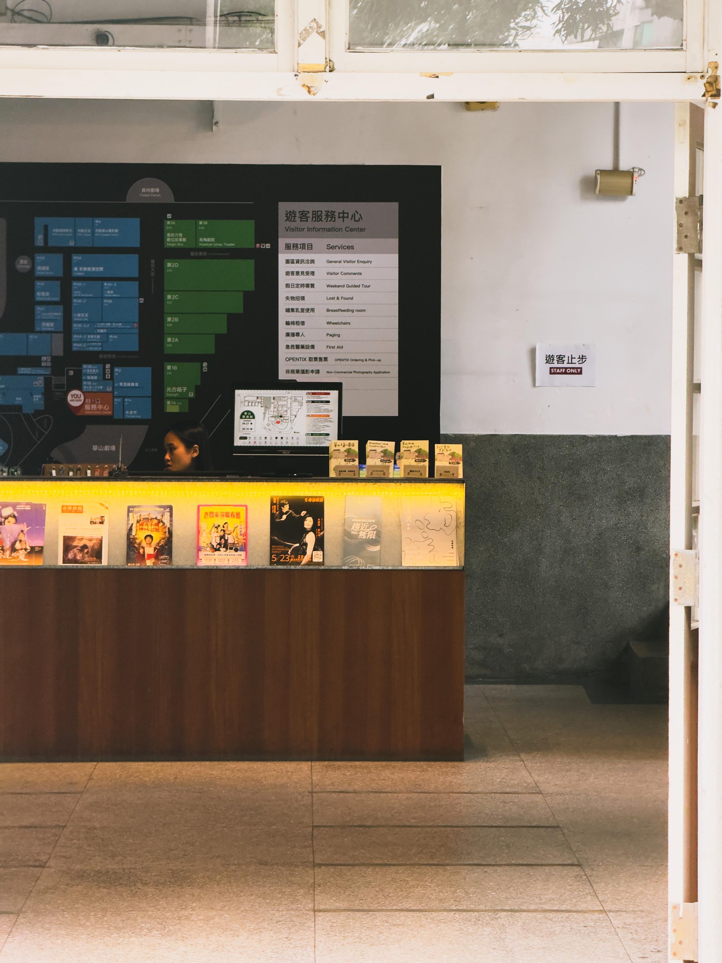 A visitor information center with a display of brochures, a sign indicating staff only, and a map or information board on the wall.
