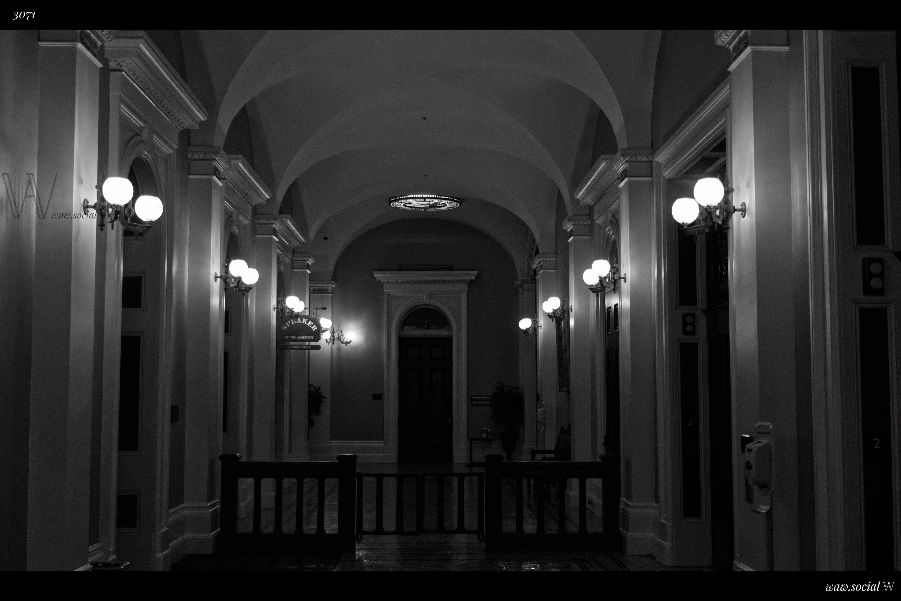 A black and white photo of a hallway in the California State Capitol in Sacramento, California.
