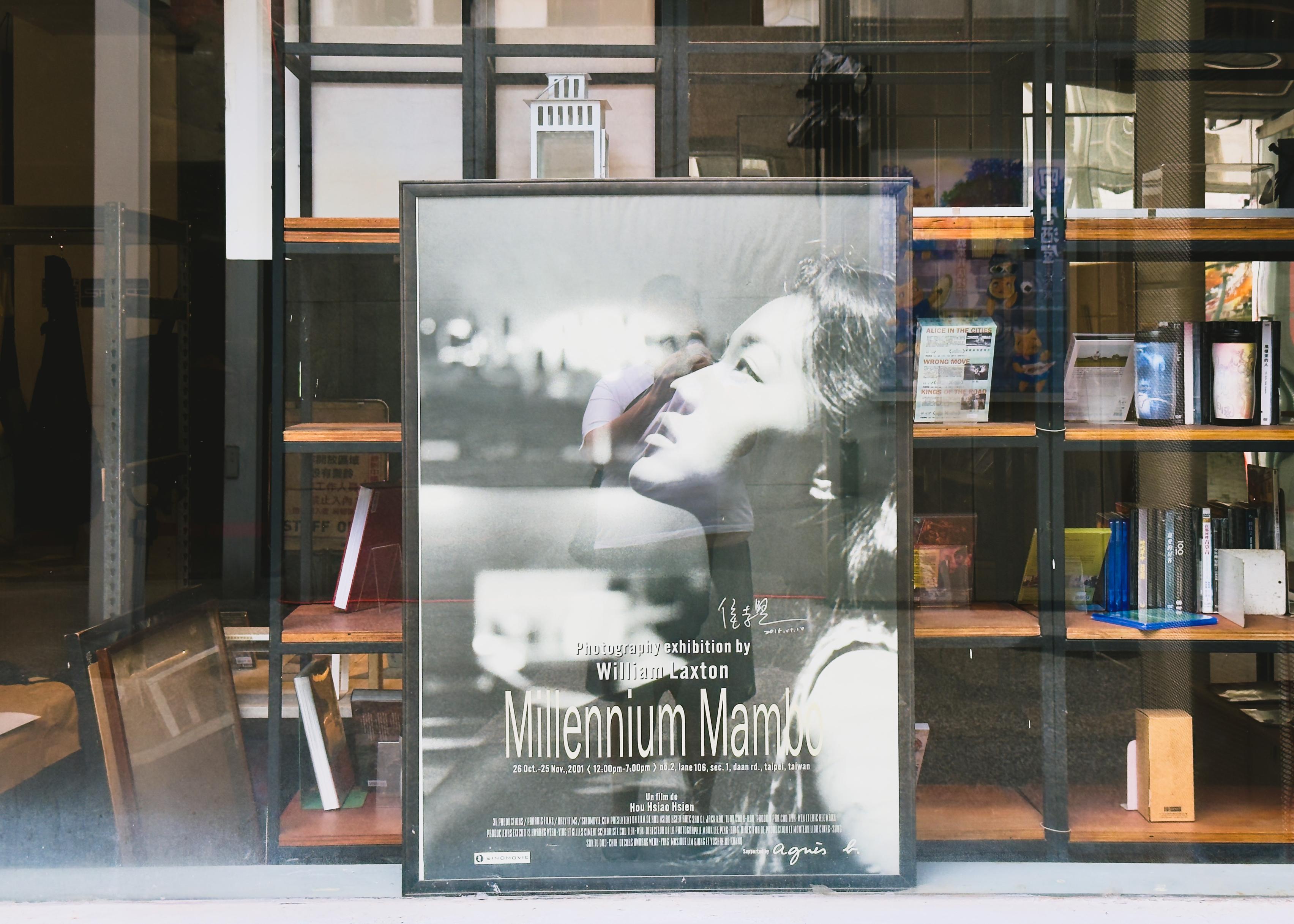 一張黑白照片中的女人側臉特寫，旁邊是“Millennium Mambo”展覽的海報，展出時間為2001年10月26日至11月25日。