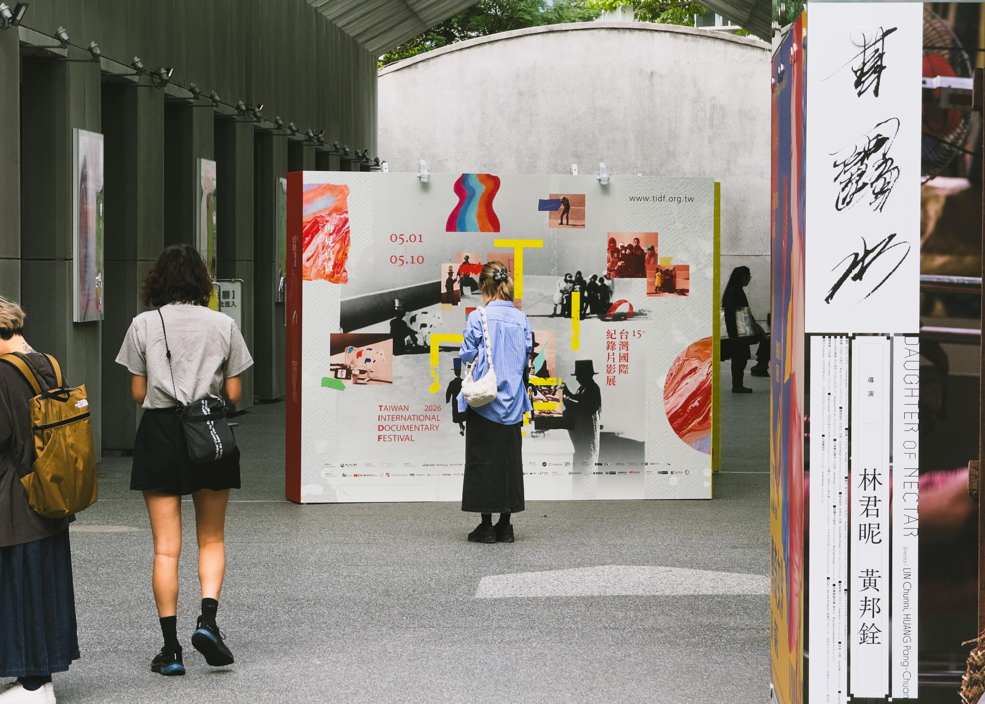 台湾国际纪录片展宣传海报和观众在展馆外观看展览。