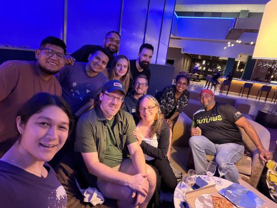 Photo with many smiling people posing for the camera in a hotel lobby 