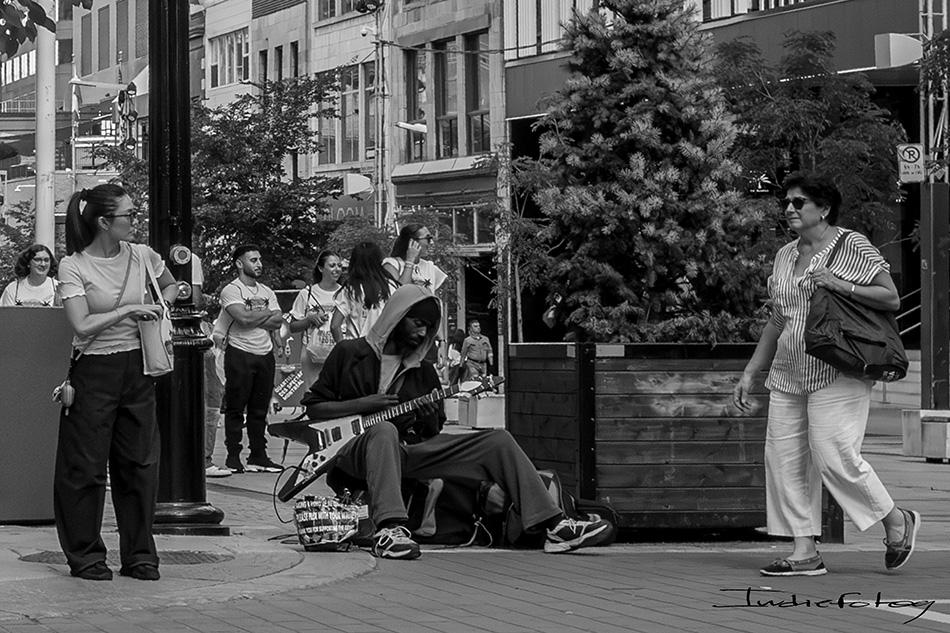 A street musician playing his Flying V guitar, in the middle of a street crossing,