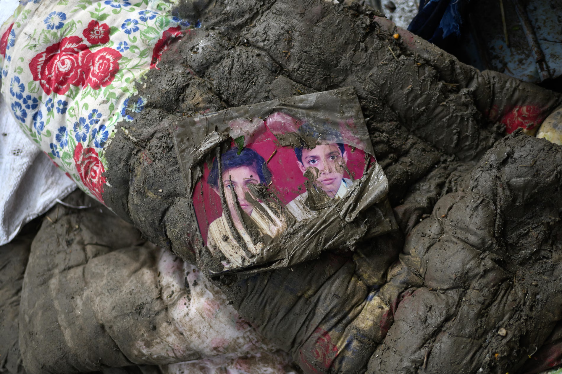A photograph of a young woman and a boy on a mud-coated mattress.