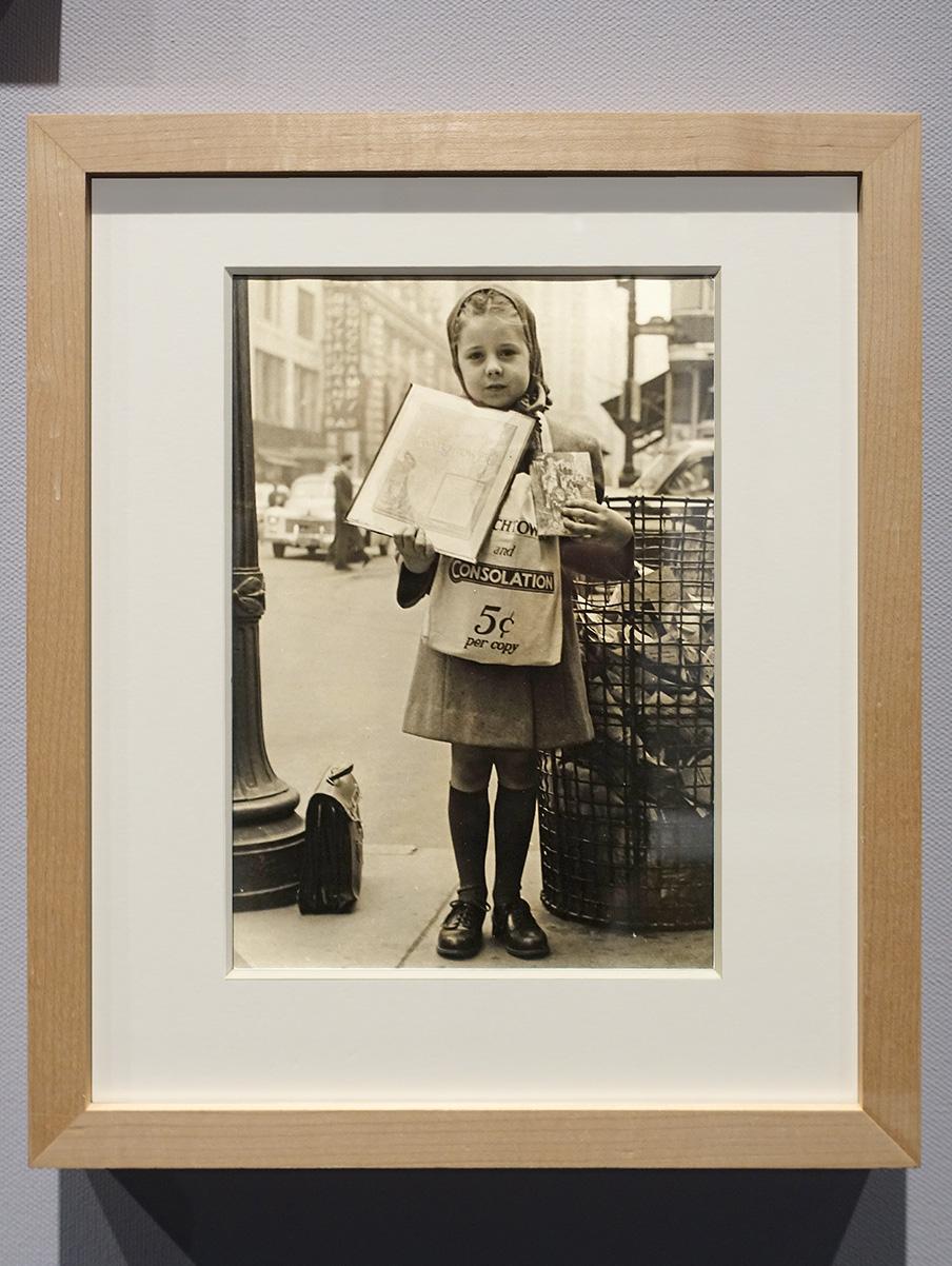 Een zwart-wit foto uit New York uit 1940 waar een klein meisje van een jaar of acht, ogen de wachttoren verkoopt voor vijf dollar cents. Om haar nek hangt een linnen tas vol met edities. In haar rechterhand laat ze een exemplaar van de wachttoren zien en in haar linker hand een of andere bekeringskaart. Het meisje is keurig gekleed met zelfs een sjaal om haar haar, zwarte gepoetste schoenen, kniekousjes. Achter haar staat een grote volle afval container. Haar schooltas staat naast die voet van een straatlamp. In de achtergrond is nog net een New Yorkse straat zichtbaar met een auto en een man. Het laat goed de armoede in New York zien.
