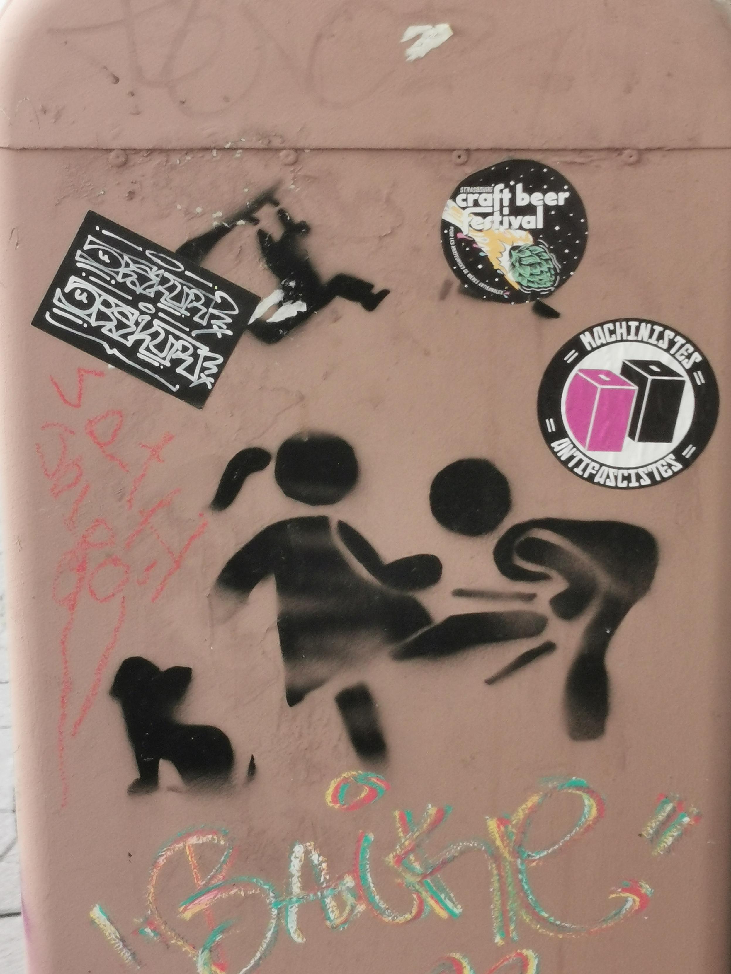 Divers pochoirs et stickers militants sur un mur.