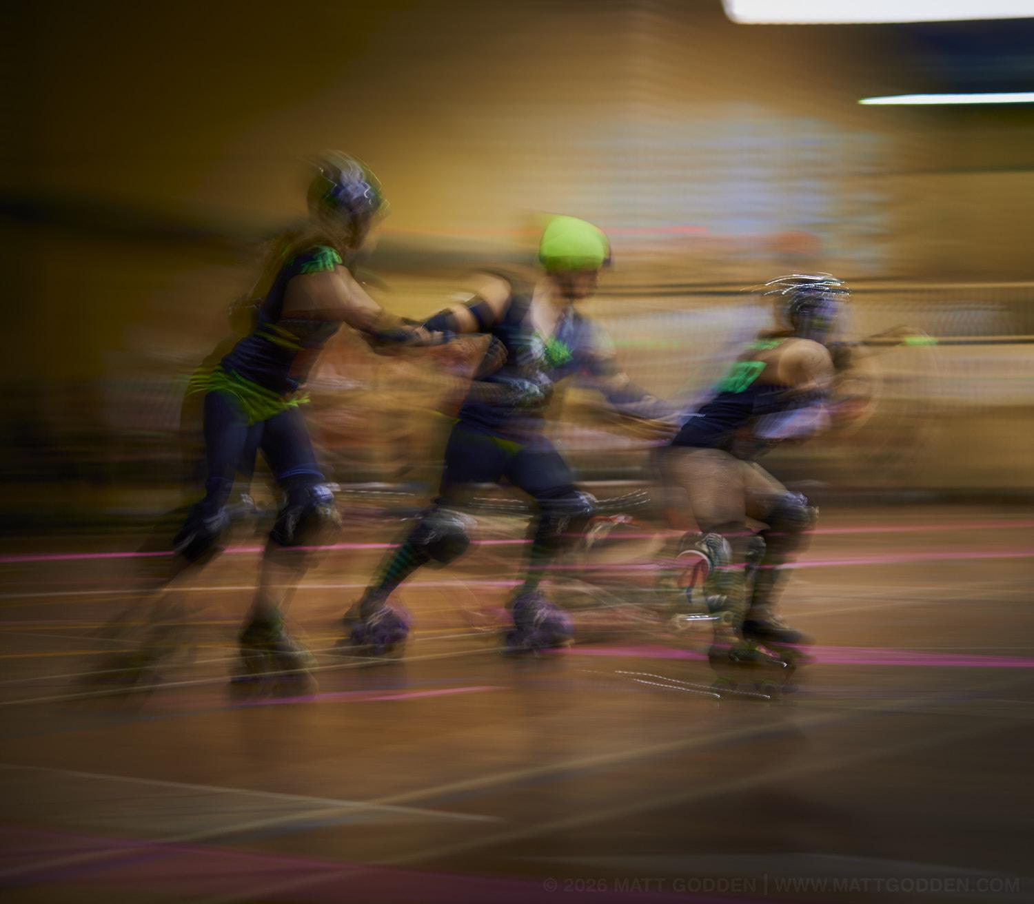 A long exposure image of roller derby competitors from the D'Viants (lime green), and the Screaming Assault Sirens (red). 2013/11/09