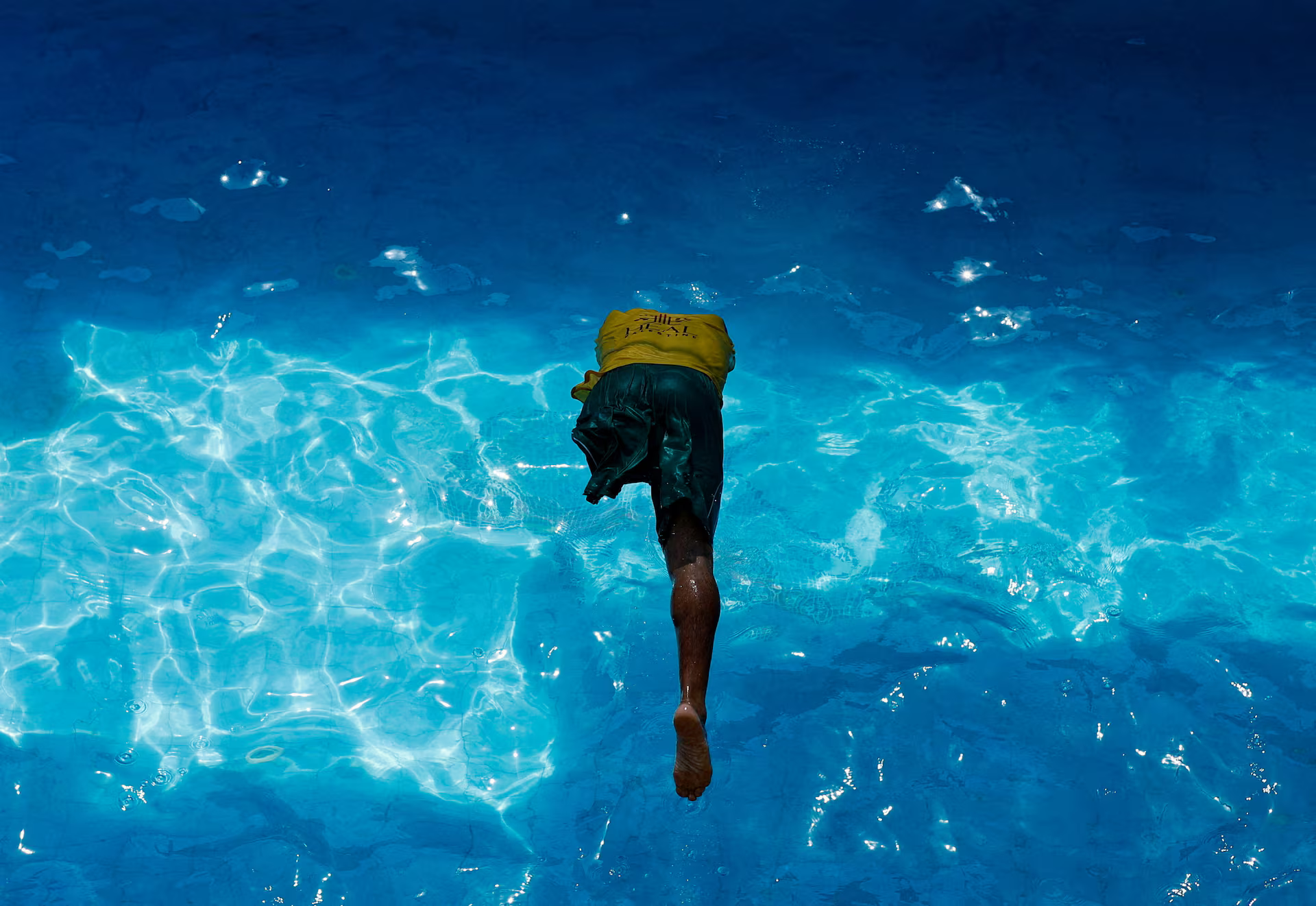 A swimming coach jumps into the water.