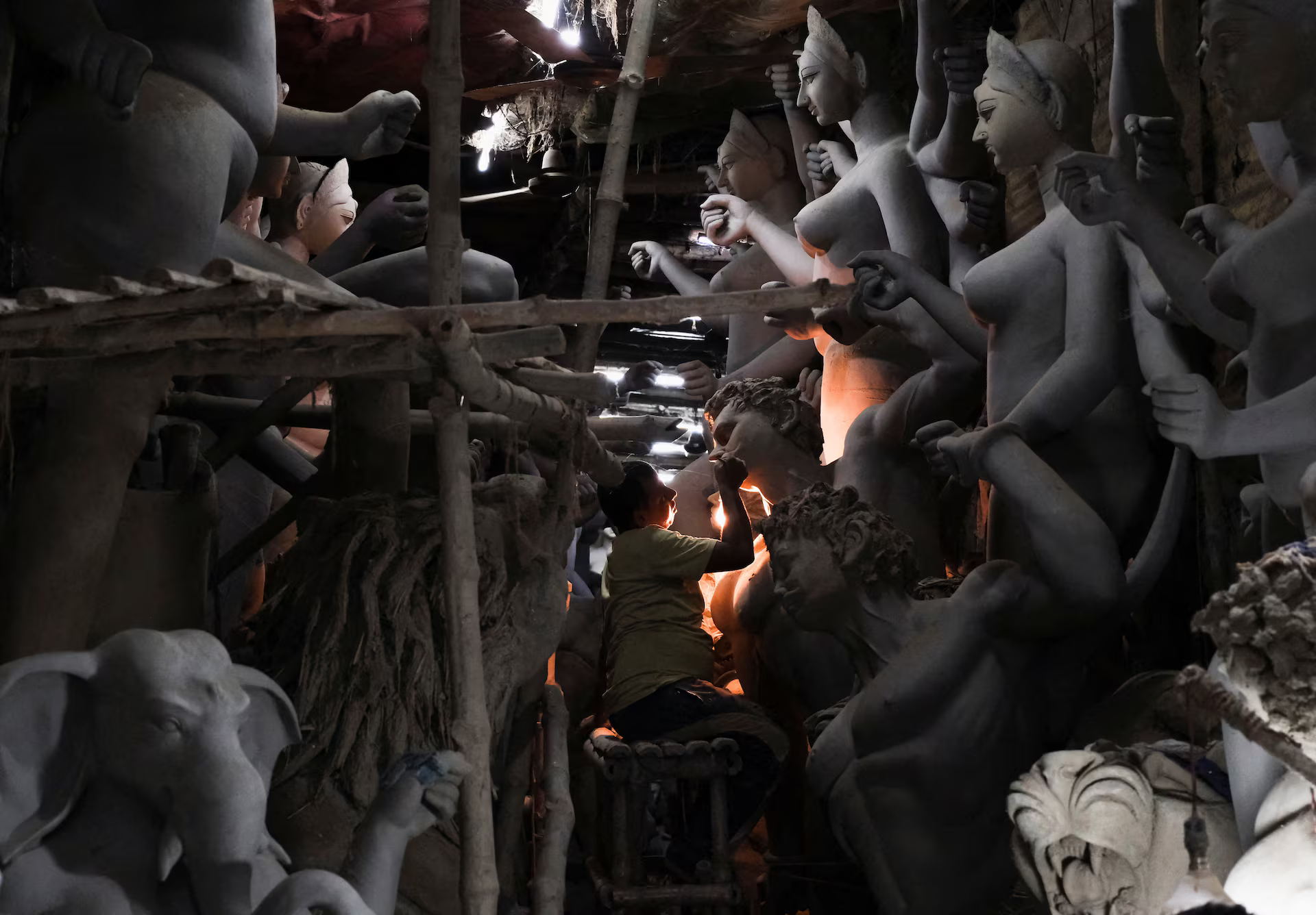 An artisan sculpts an idol inside a workshop.