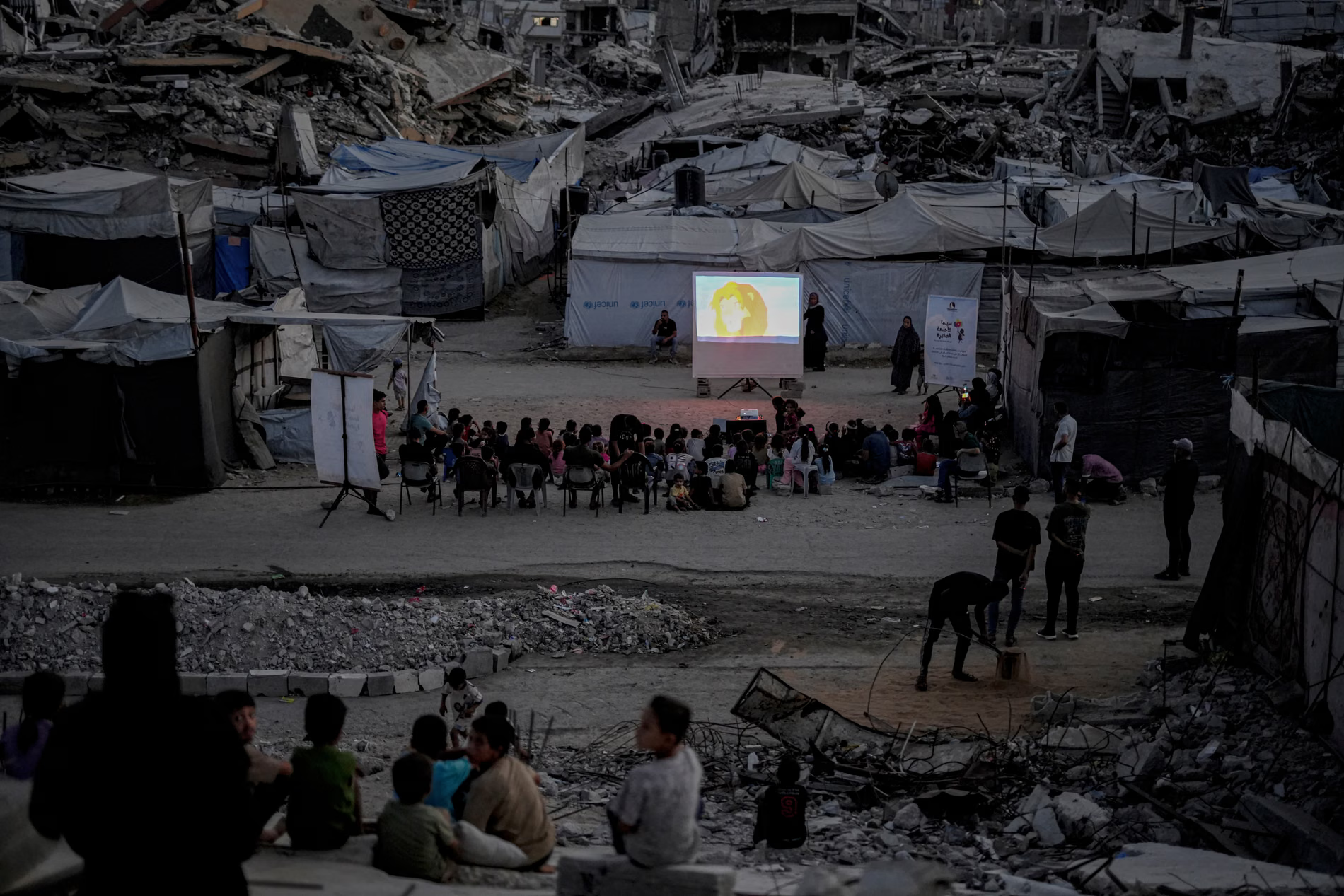 Children in an outdoor cinema among ruins.