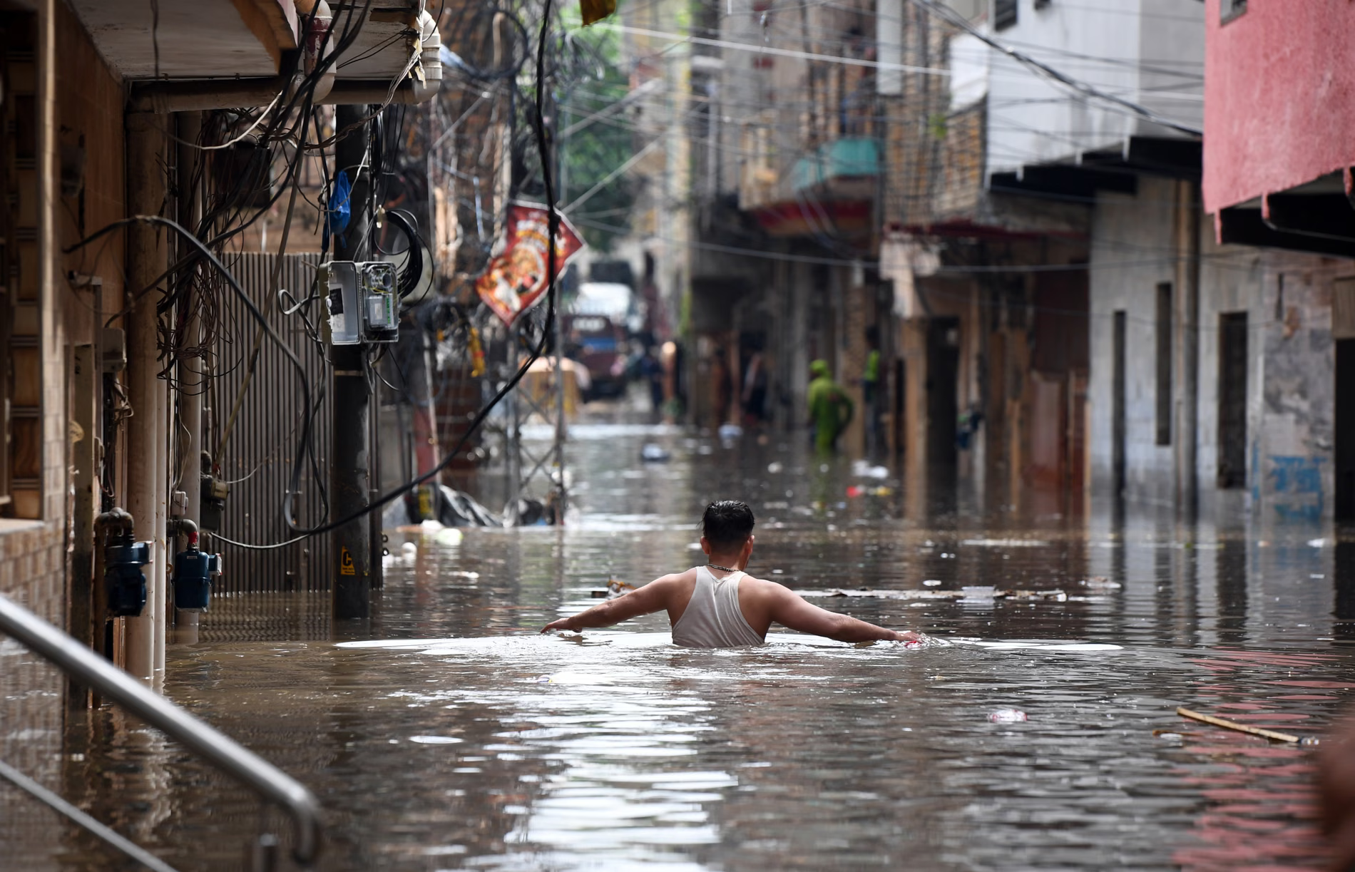 A man submerged to his chest in a flooded street.