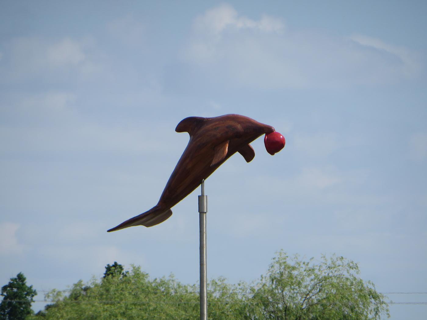 sculpture d'un dauphin sautant avec un bonnet rouge dans la bouche