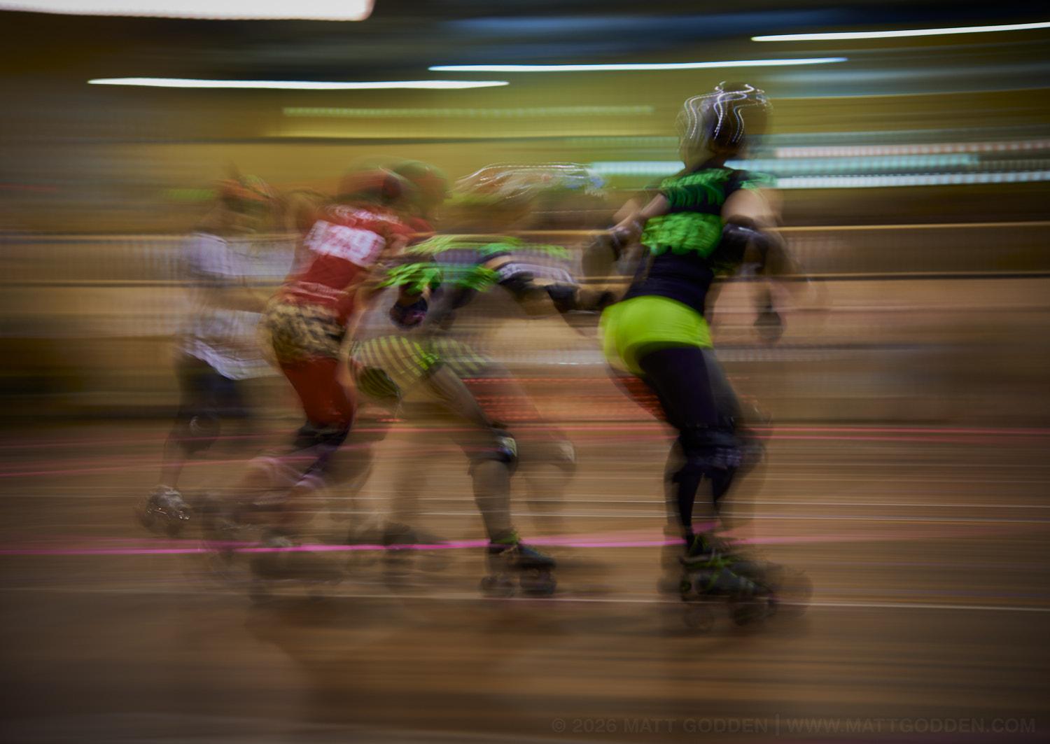A long exposure image of roller derby competitors from the D'Viants (lime green), and the Screaming Assault Sirens (red). 2013/11/09