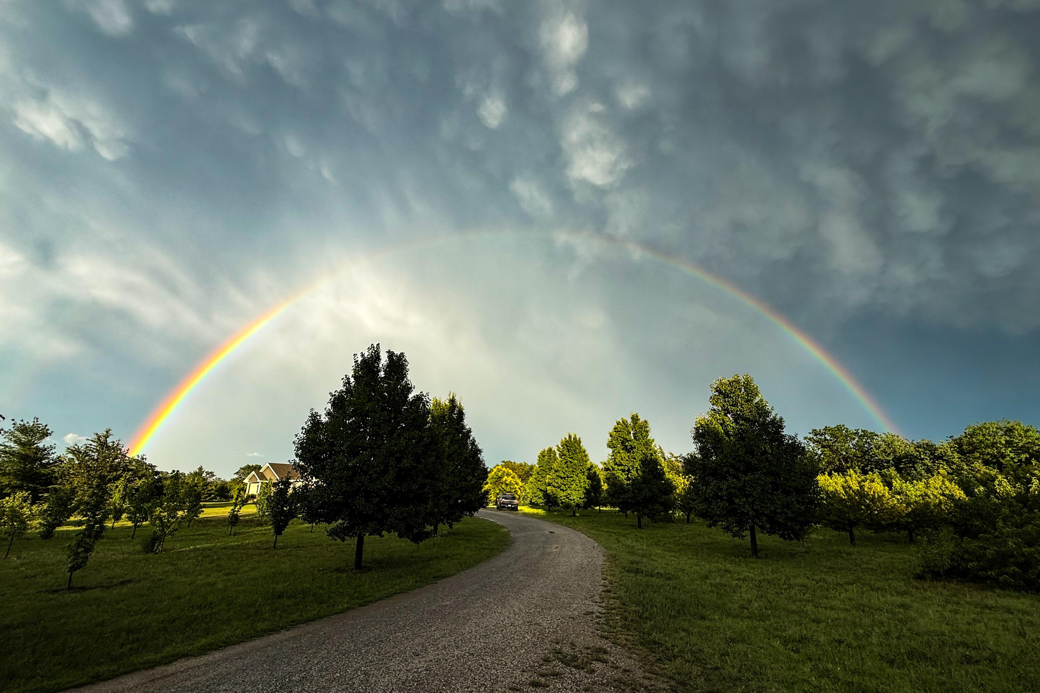 A full rainbow appears on the horizon with dark clouds as a backdrop.