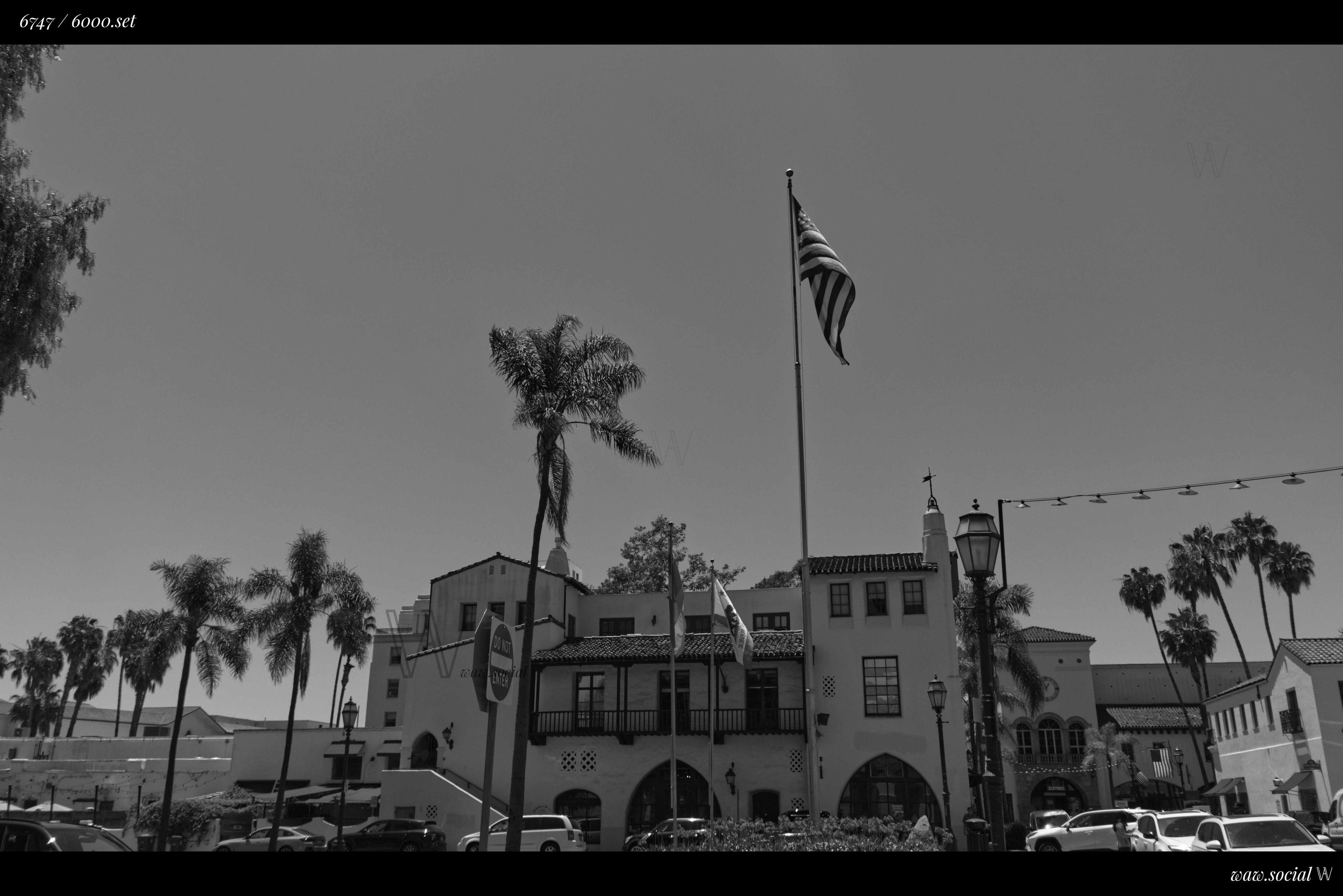 A black and white photo of a building in Downtown Santa Barbara, California with the US, California and Santa Barbara flag in frame.