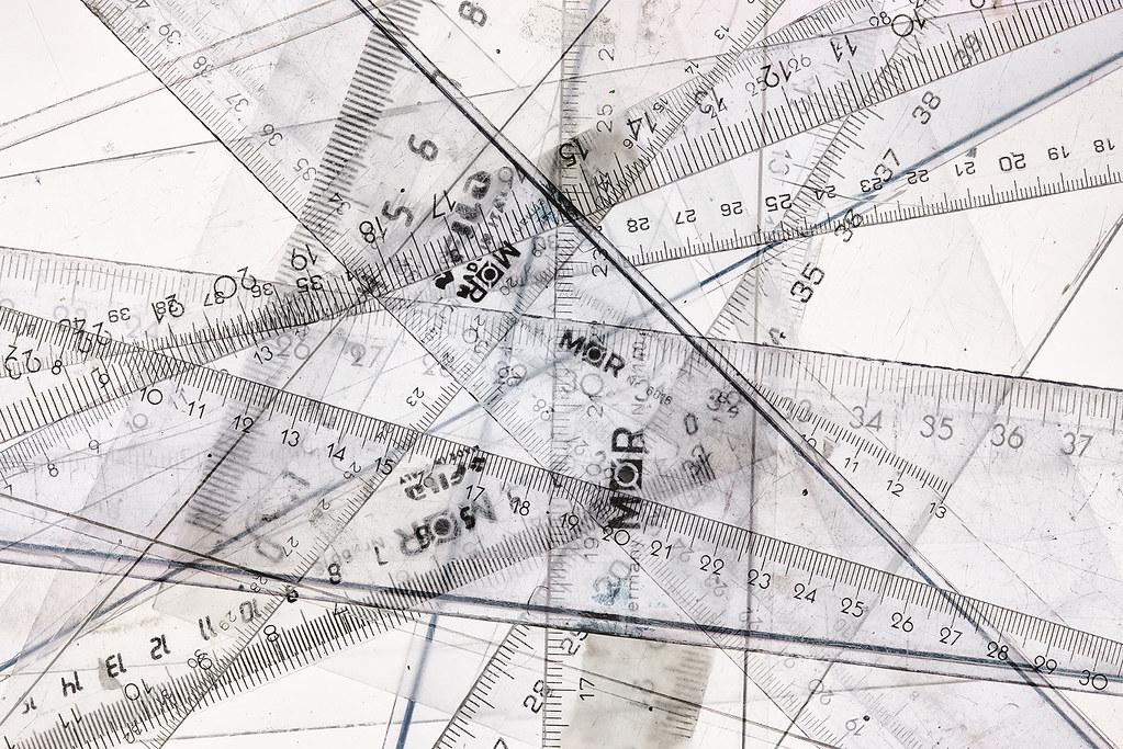 A composite image of multiple transparent plastic rulers, many of which are of the brand MOR, overlapping on a white surface, creating a jumble of lines and various measurements in centimeters and millimeters.
