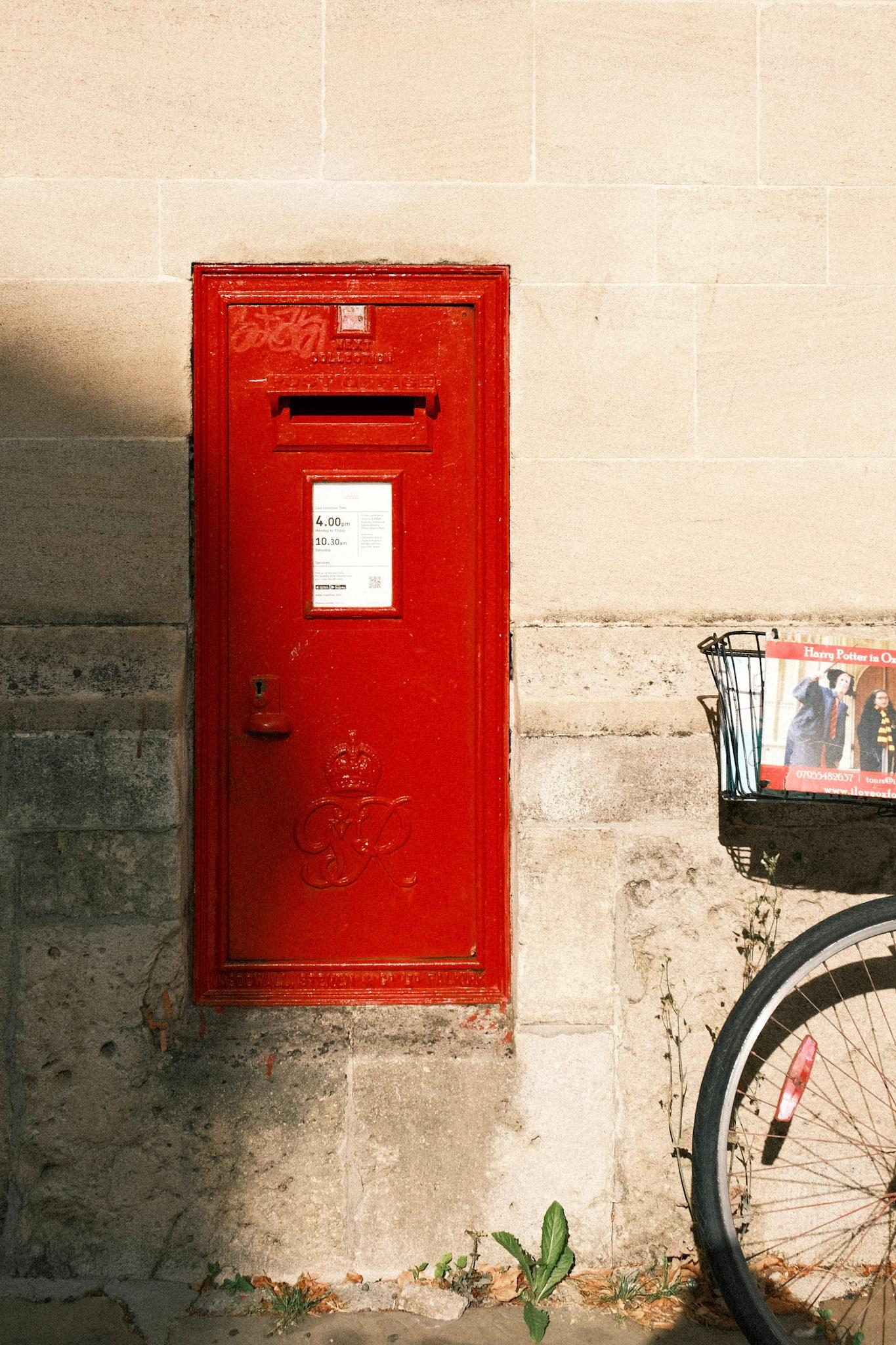 A bright Red letterbox with a bike next to it