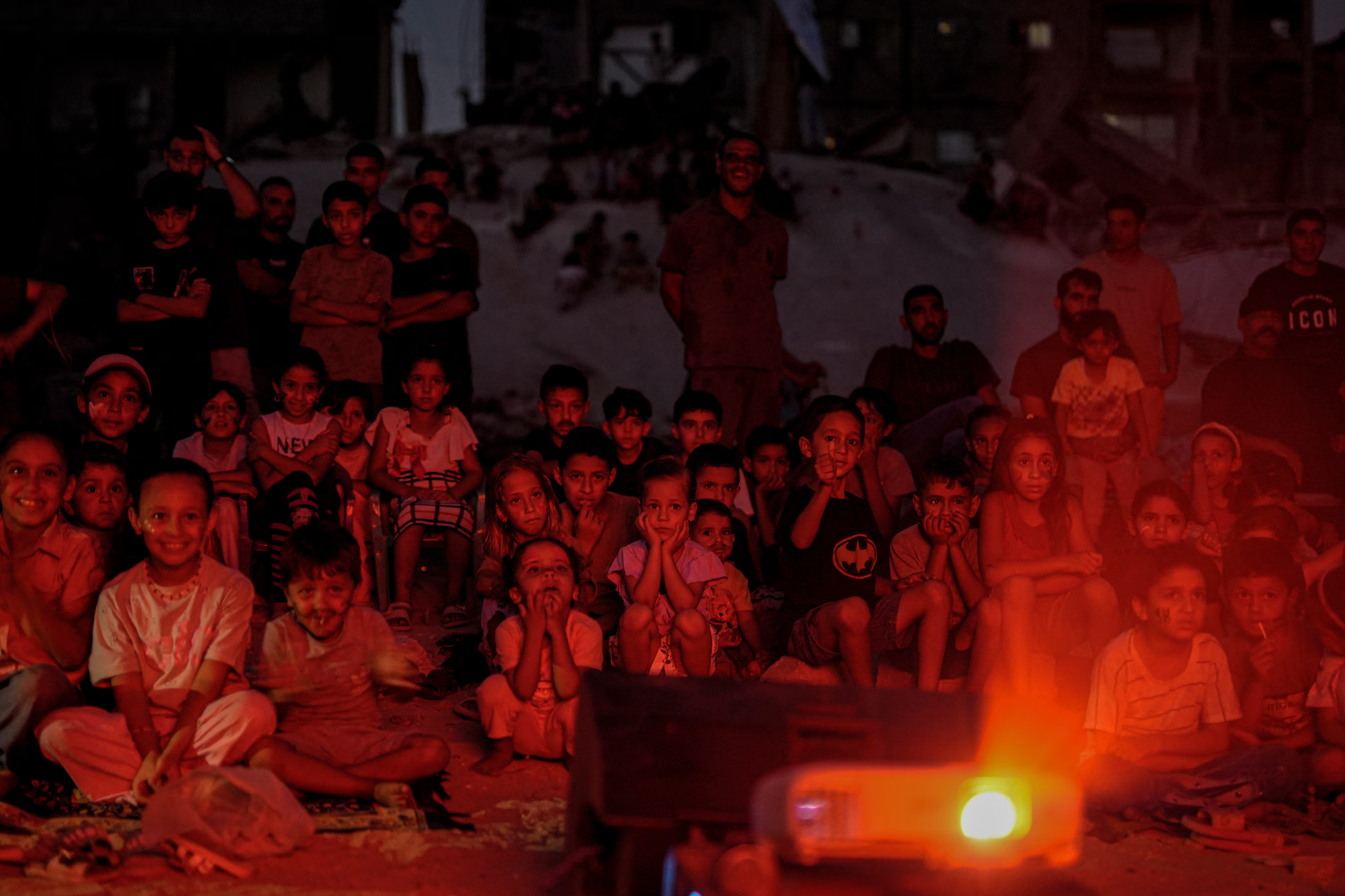 Palestinian children watch a film screening in an outdoor cinema.