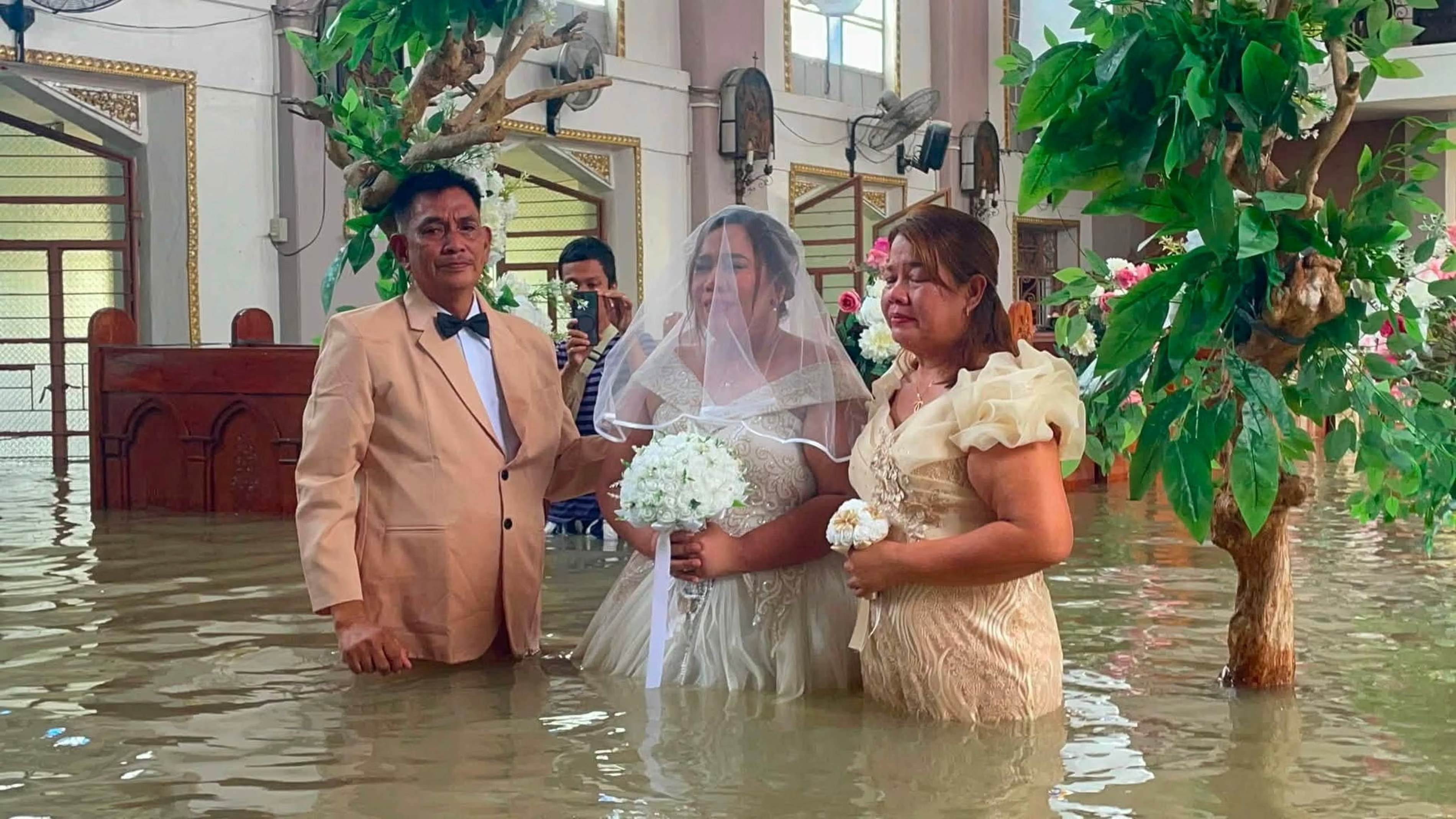 A bride walks the aisle of St John the Baptist Parish as a wedding continues despite flood waters filling the church.