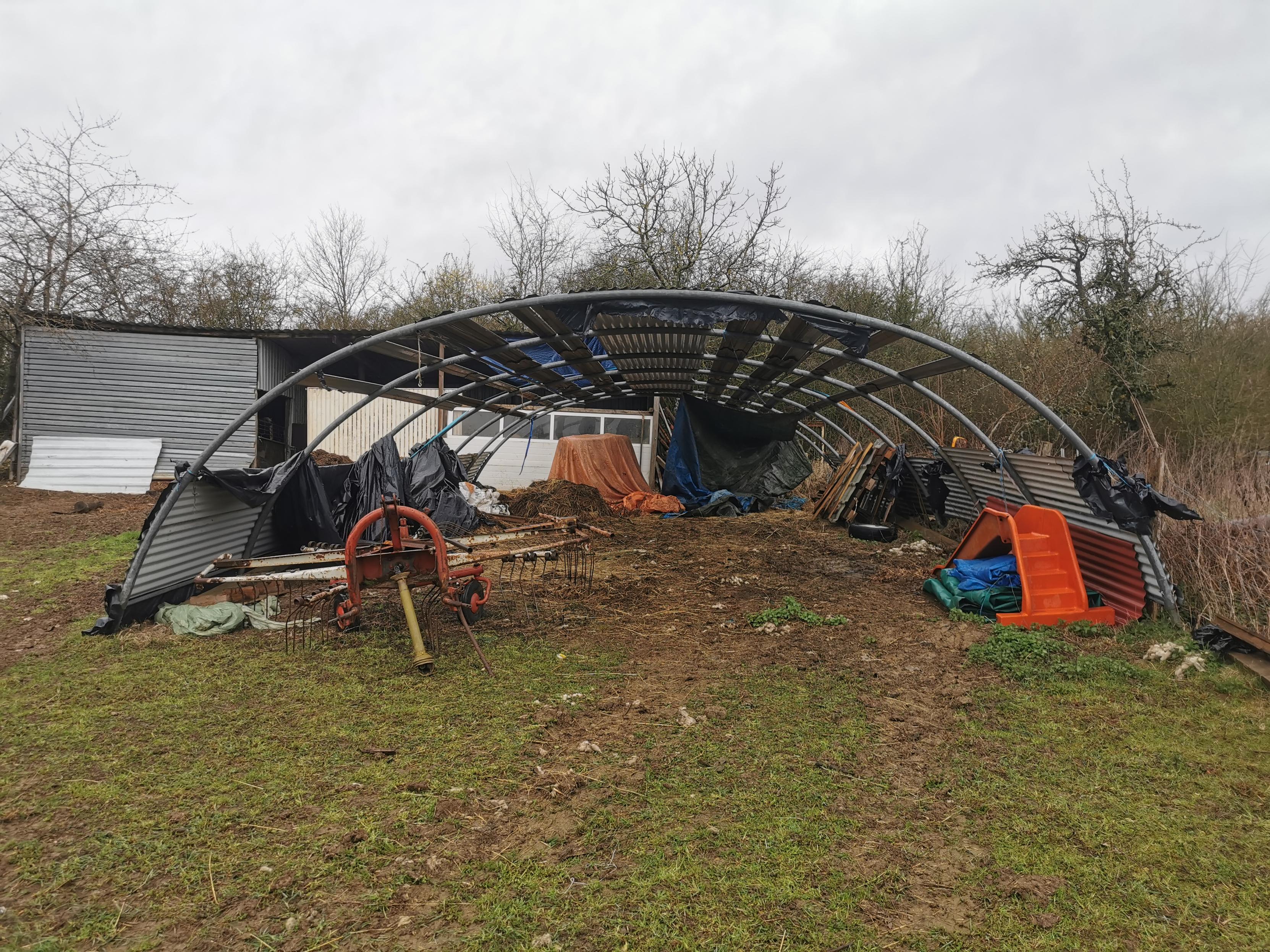 Une serre/tunnel de stockage dont la bâche à été arrachée.