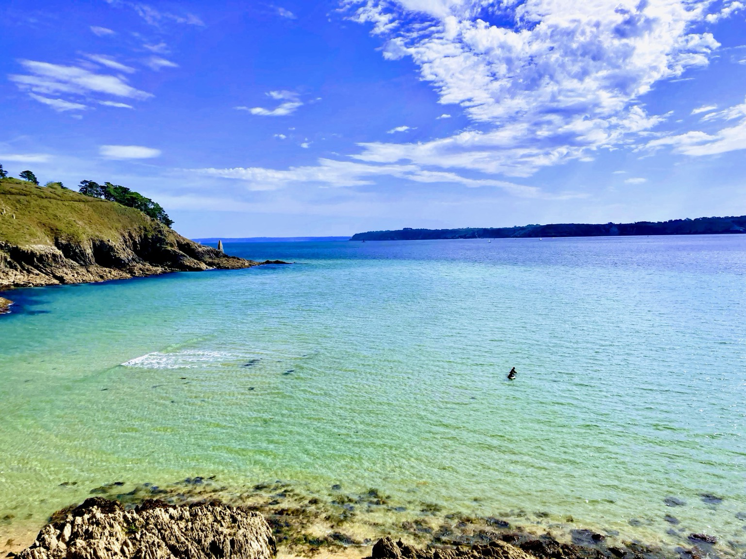 Derrière le phare du Minou. Plouzané. Plan d’eau glassy, turquoise, formant une lagune bordée d’une falaise végétale, le goulet de Brest aux eaux profondes et la pointe des espagnols en face à l’horizon.