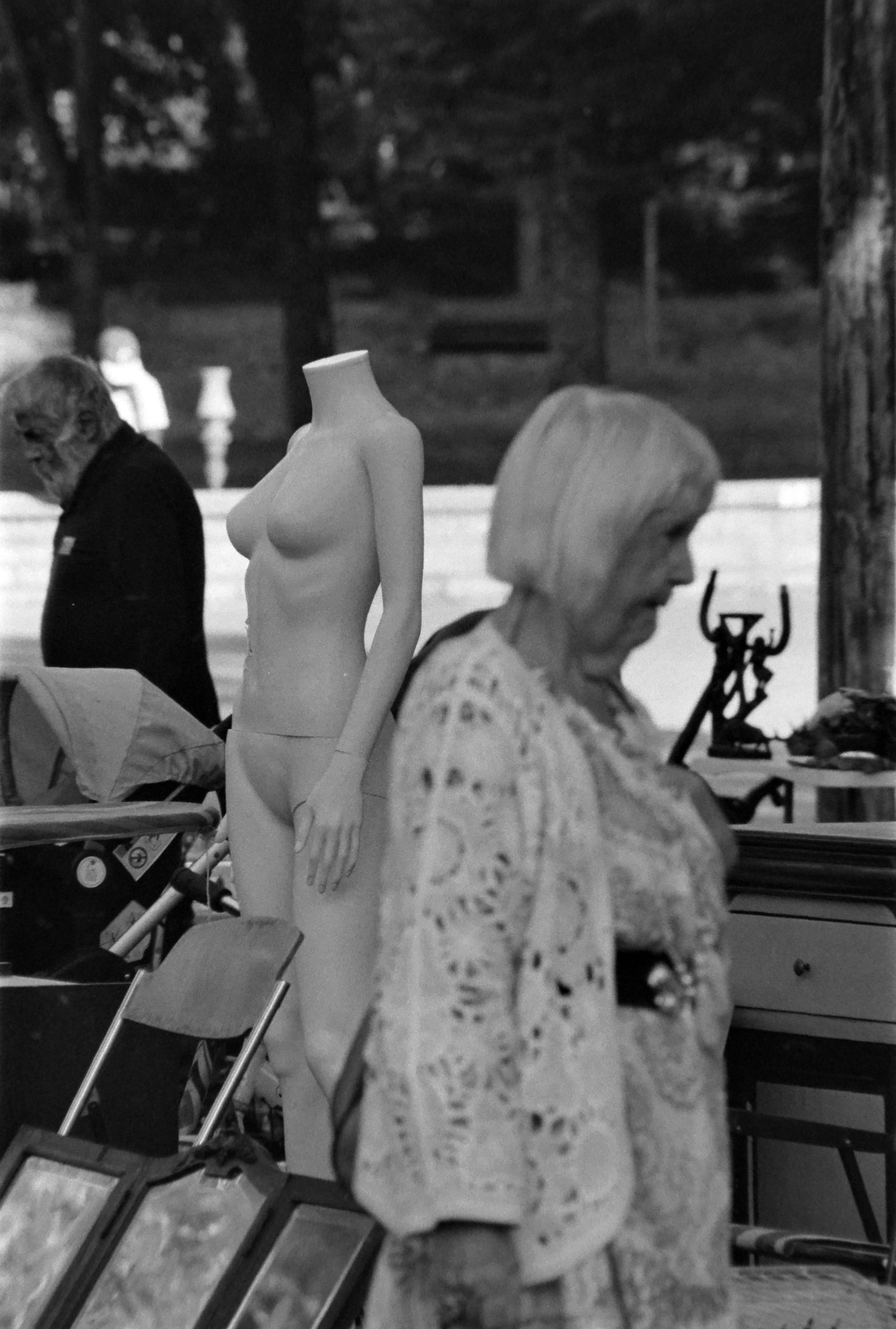 une femme agée passe devant un mannequin dénudé