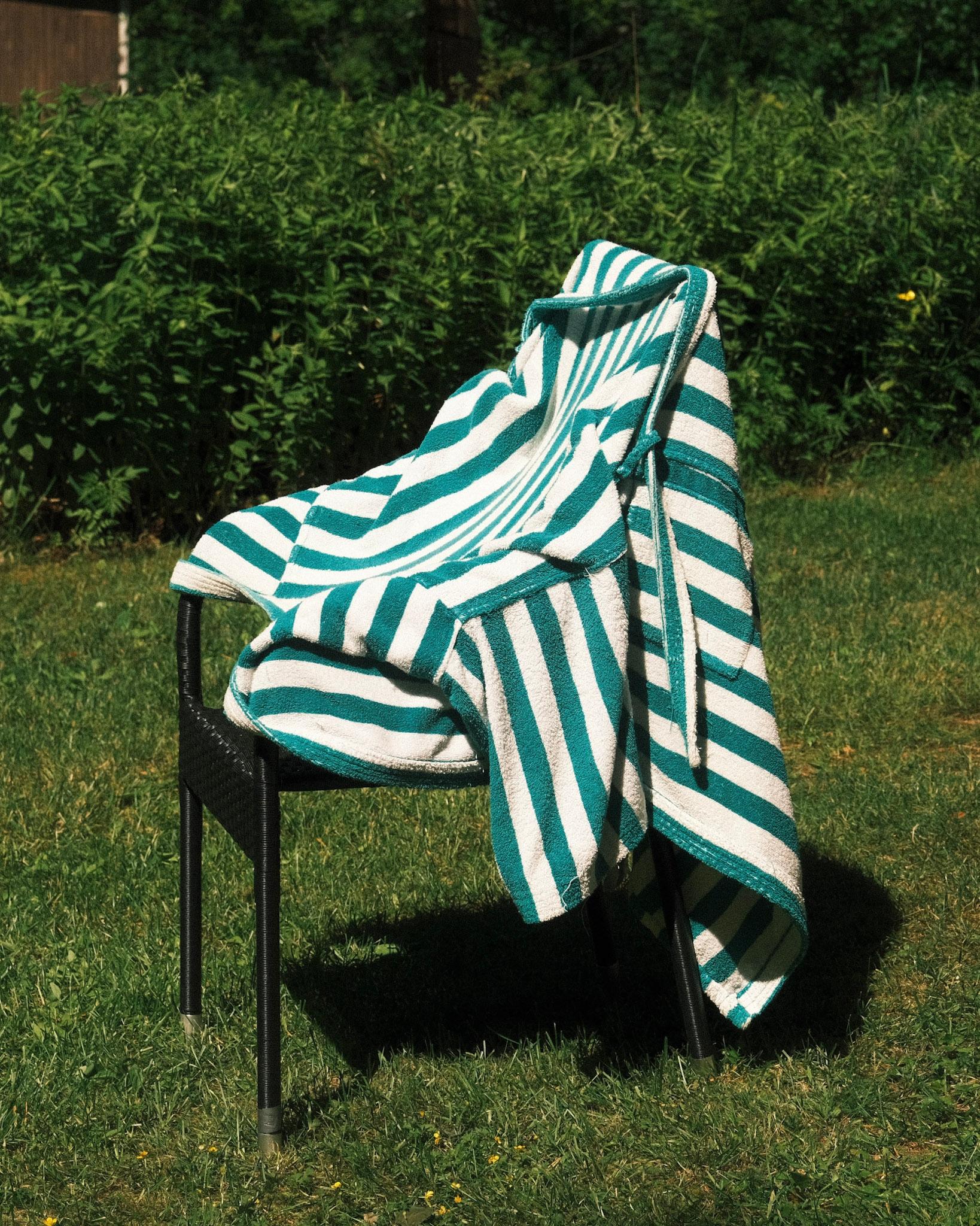 Green and white striped bath rope drying on a chair