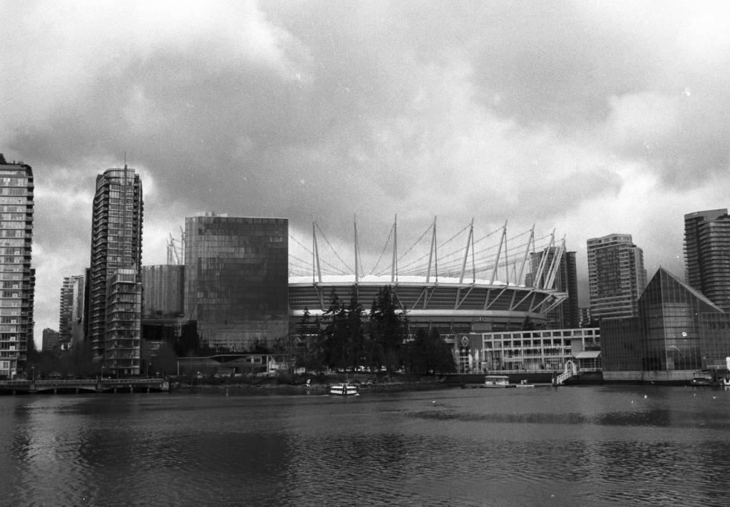 The stadium and glass towers under cloudy skies.
