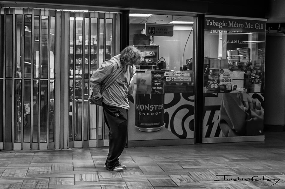 A disheveled,man passing by an ad poster for "Monster Energy" drink.