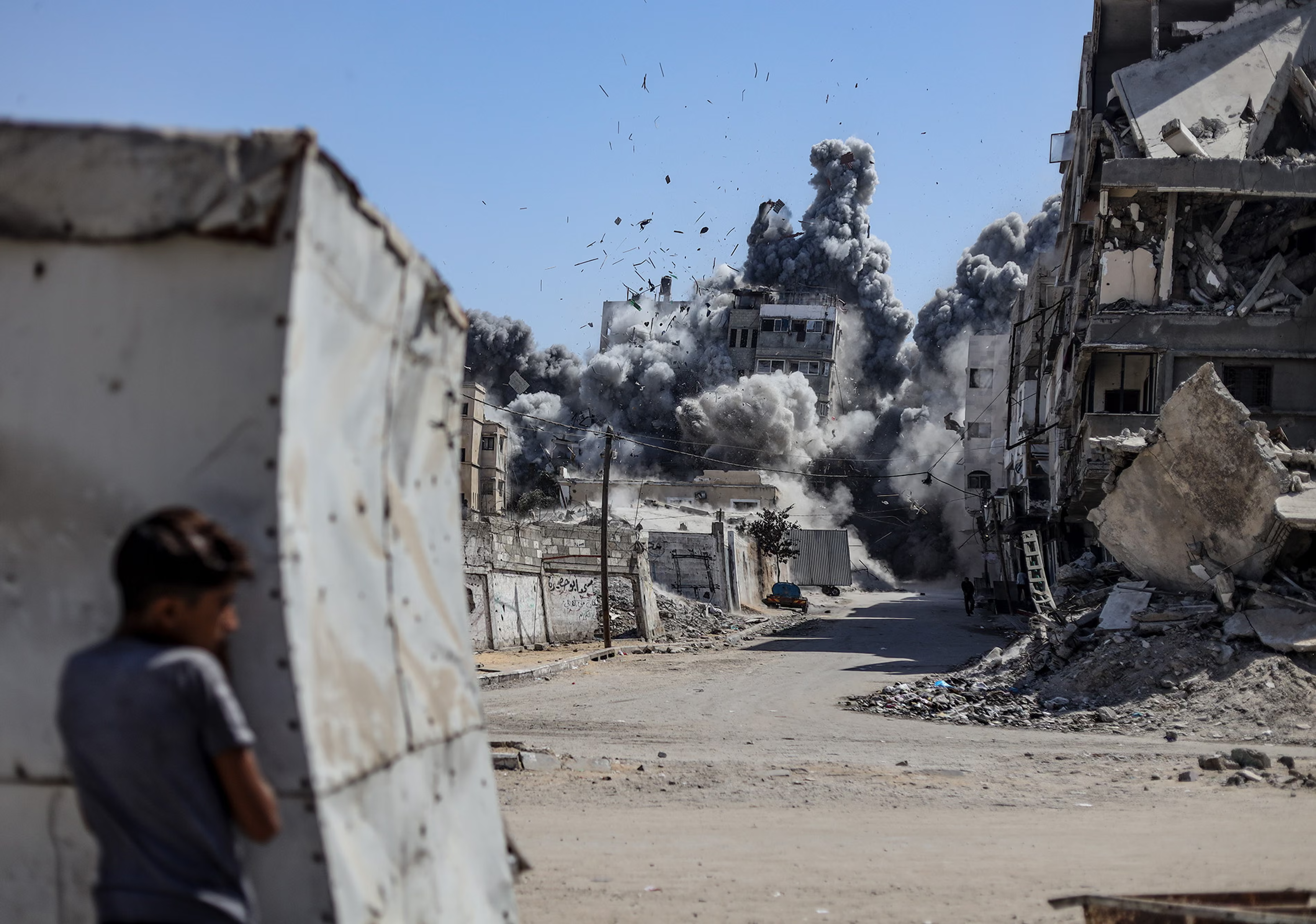 A boy watches as a building is hit by a missile in Gaza City.