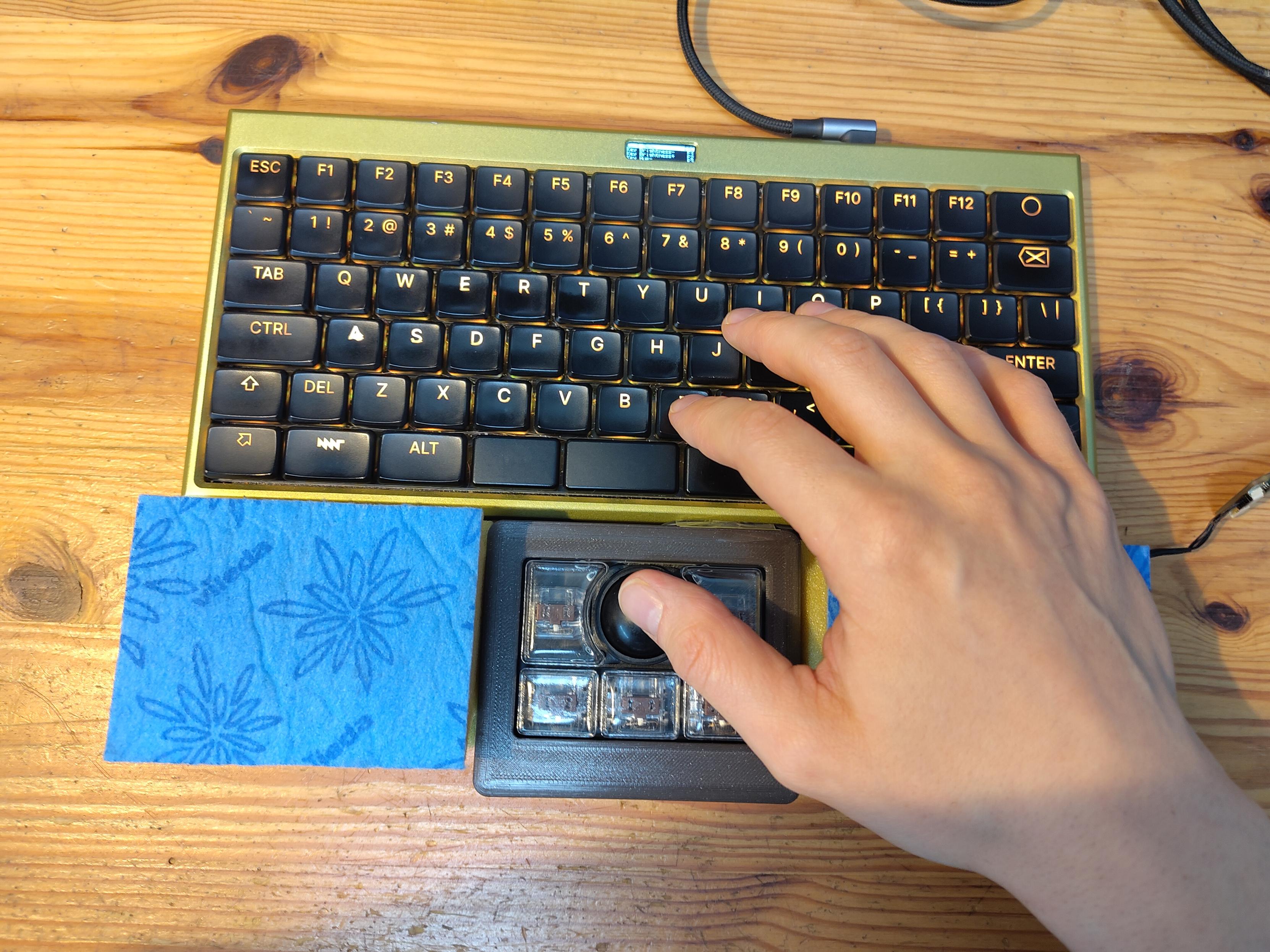 trying out a standalone usb version of the classic mnt reform trackball intended for thumb use in front of a keyboard, with vileda dishwashing sponges as stand-ins for palm rests