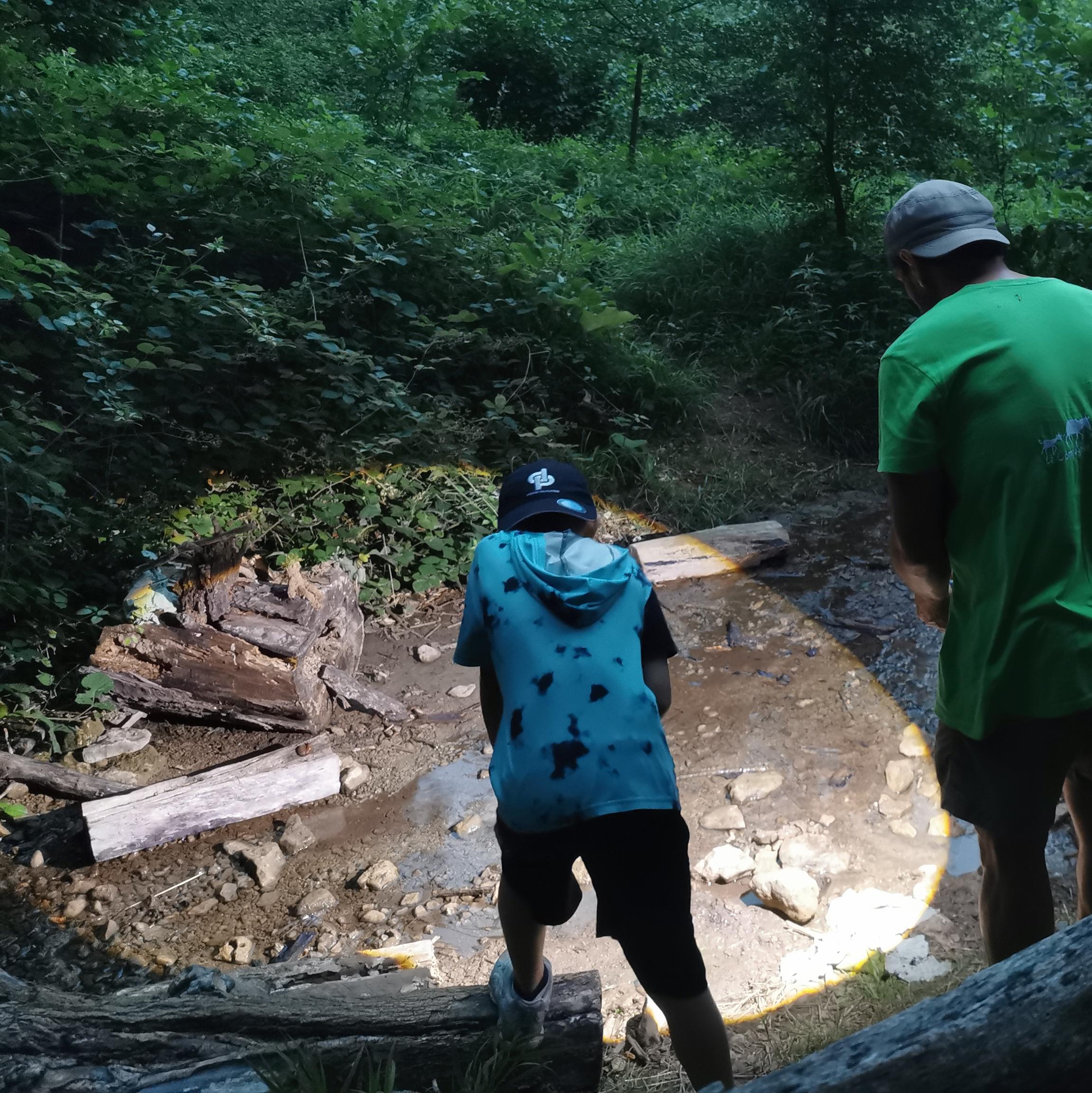 Un adulte et un enfant observent la faune d'un ruisseau à la lumière d'une lampe.