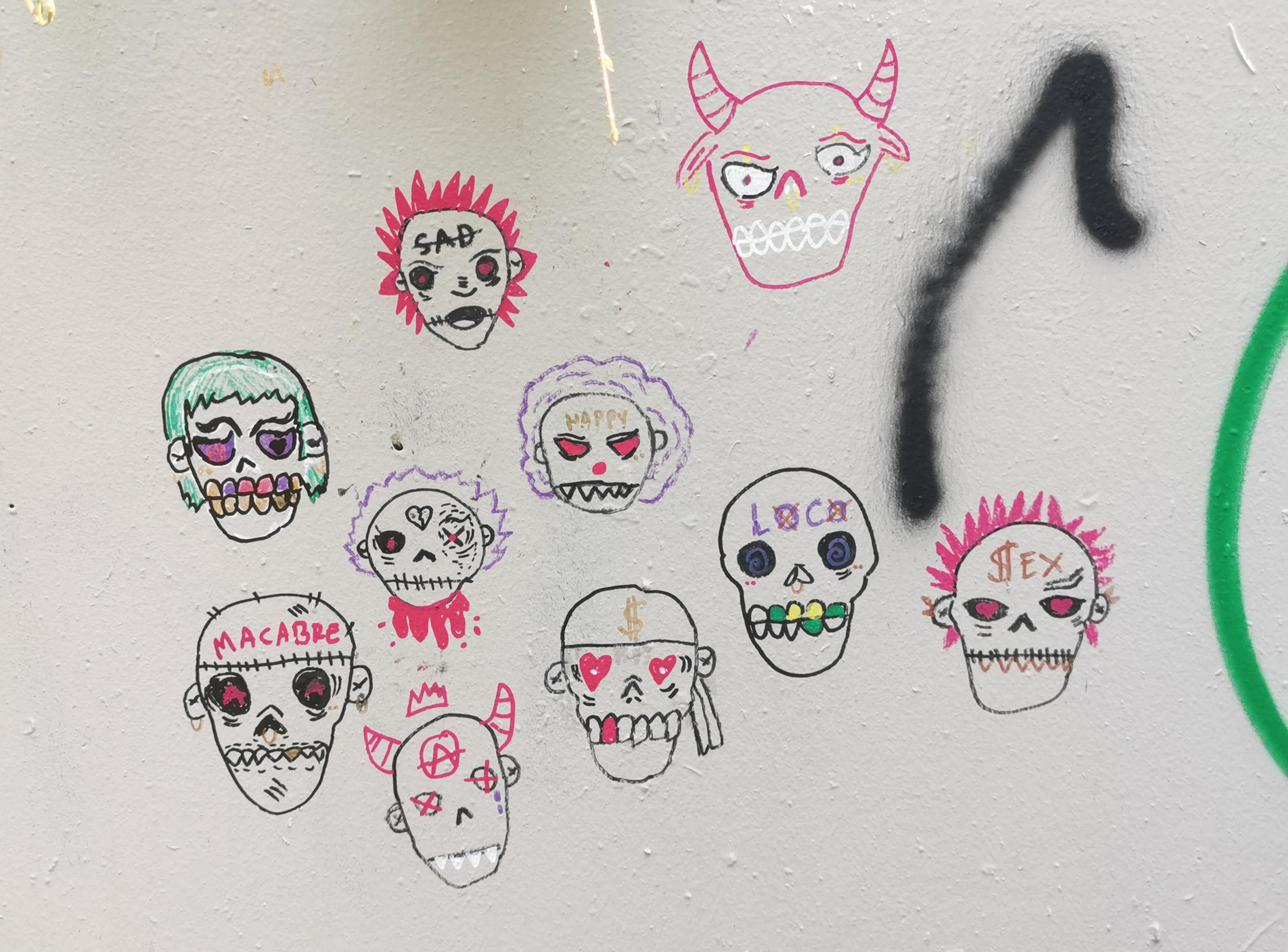 Série de têtes squelettiques ayant chacune son style sur un mur.