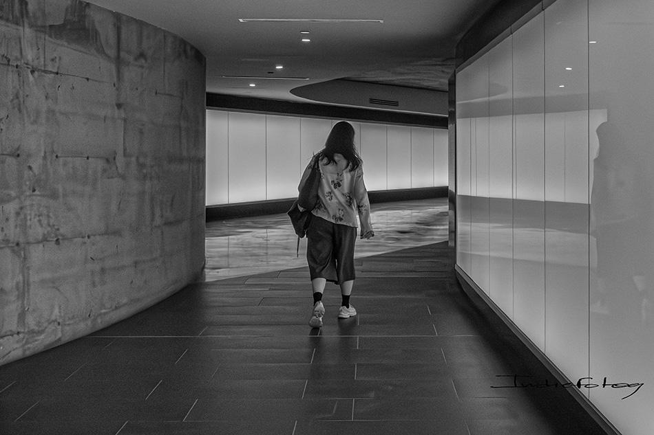 A woman walking in a corridor with no signs or indications.
