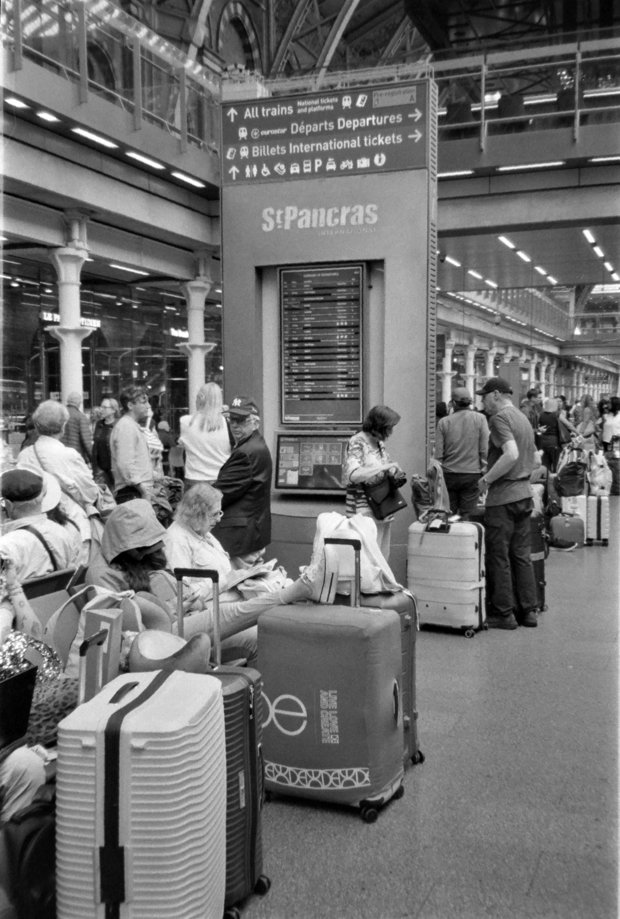 personnes attendant le train devant un panneau d'affichage