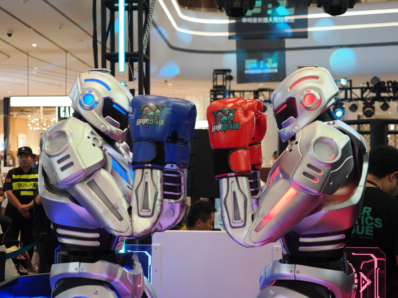 Two robots, one with red accents and red boxing gloves and one with blue accents and blue boxing gloves face each other.