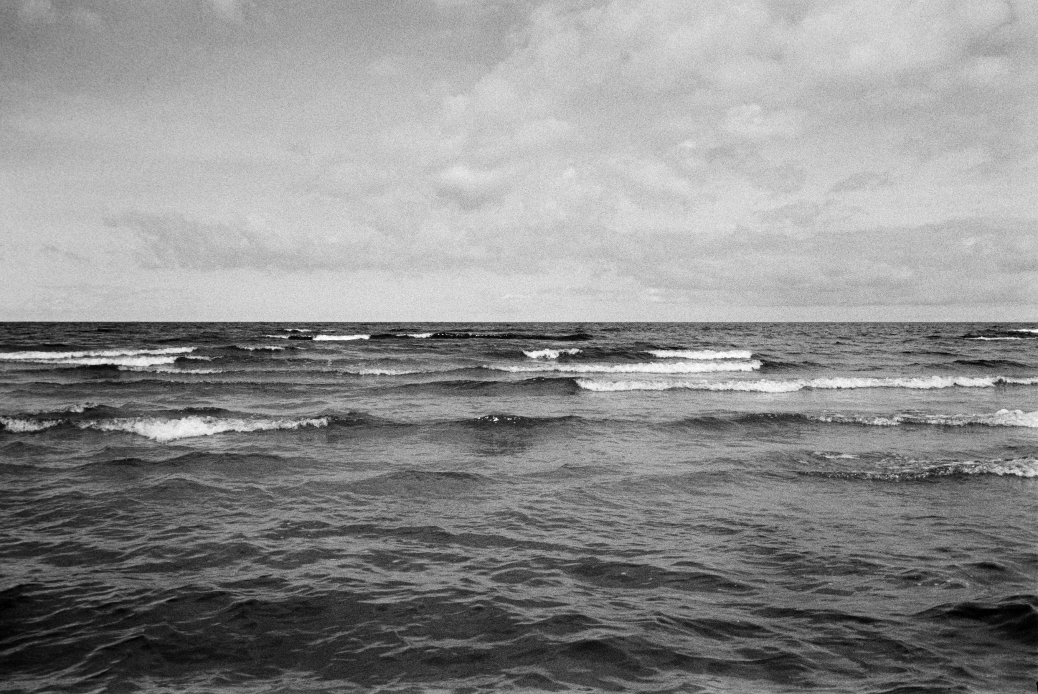 Schwarz-Weiß-Fotografie

In der unteren Bildhälfte das dunkel erscheinende Meer mit Wellen, z. t. mit Schaum. In der oberen der Himmel mit ein paar Wolken.