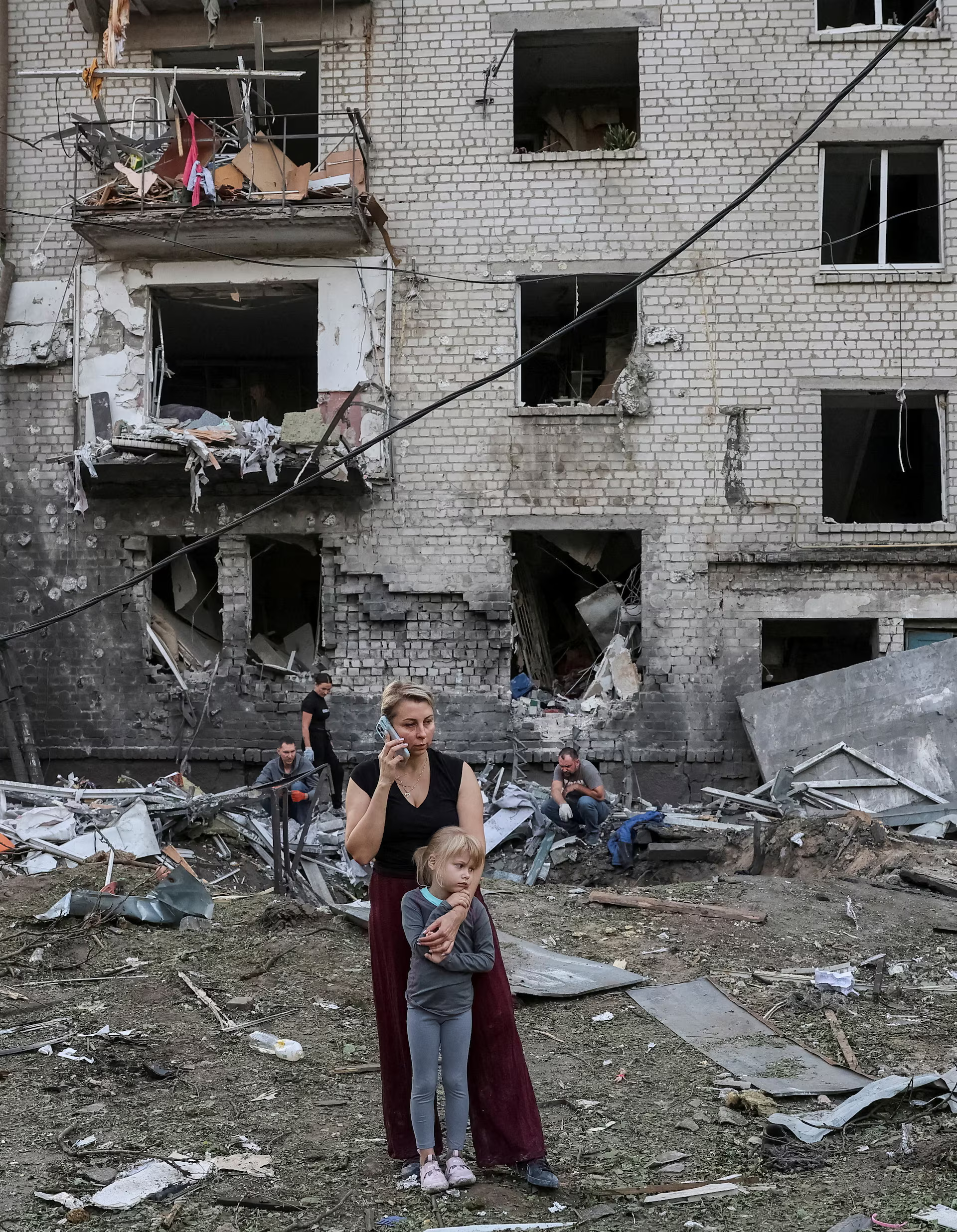 A resident Nataliia and her daughter Elia, 6, stand at a site of an apartment building damaged by a Russian missile strike, in the town of Borispil, Kyiv region, September 1. REUTERS/Stringer#photography #Ukraine #children