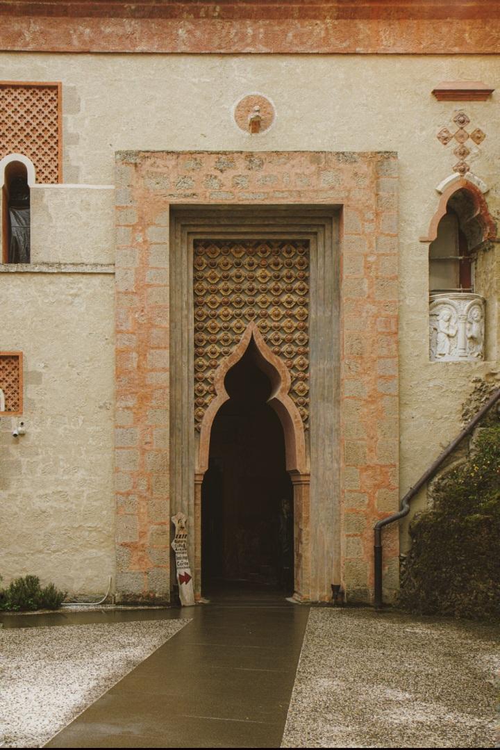 A photo of a door in Rocchetta Mattei. It Is very ornate and arched and based on the styles seen in the Alhambra/North African/Moorish/Islamic art style.
