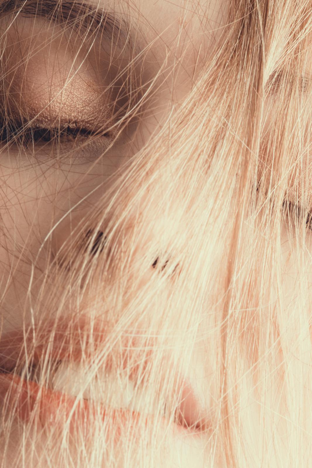 Cara de mujer rubia con el pelo por delante.